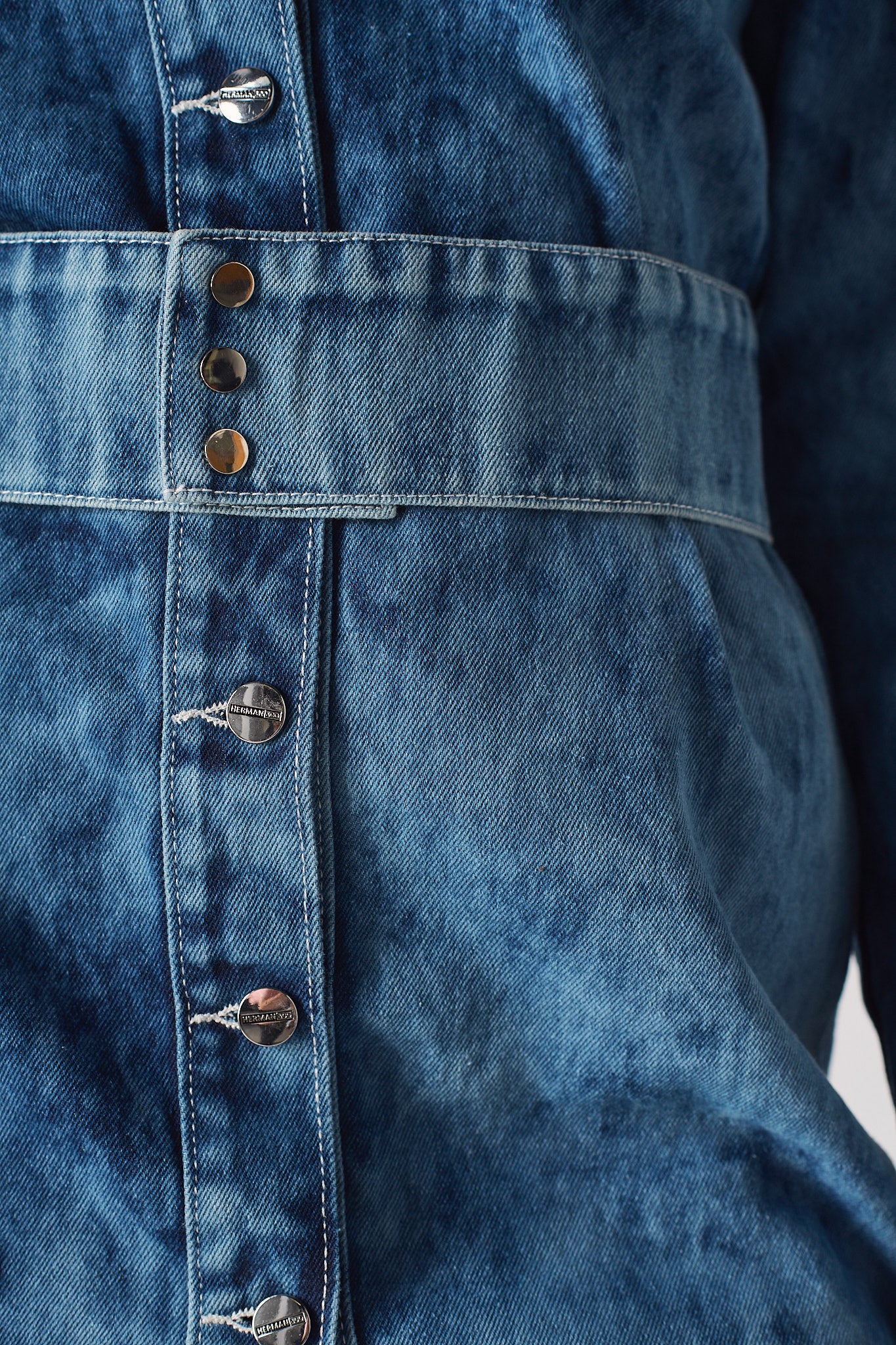 Close-up of the popper belt and branded buttons on the acid wash dress