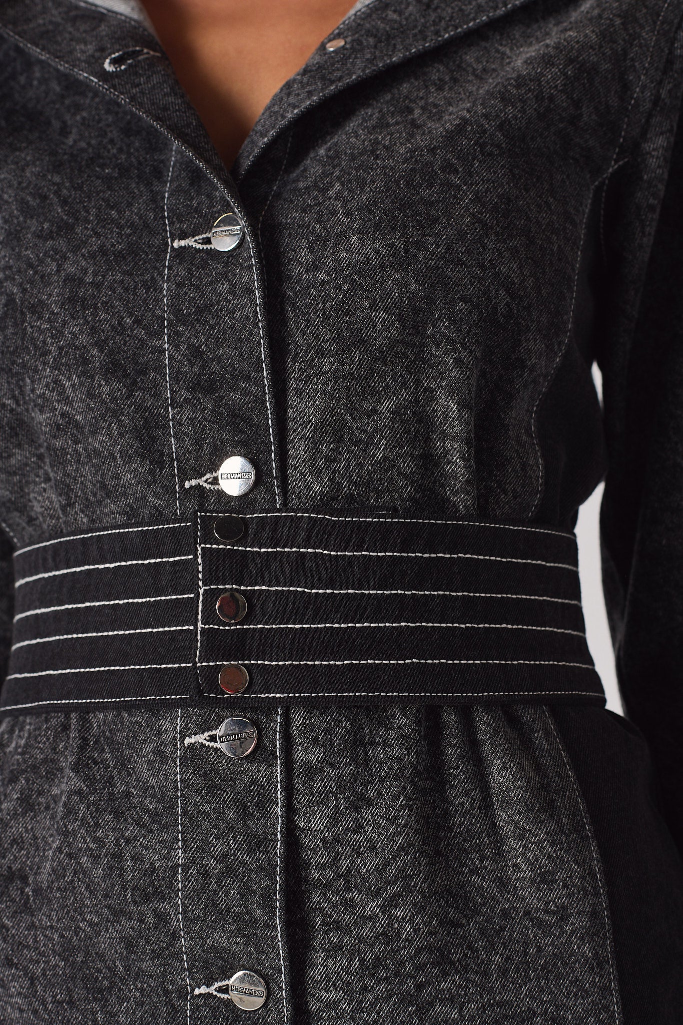 Detailed close-up of the white contrast stitching on the belt of the acid wash dress