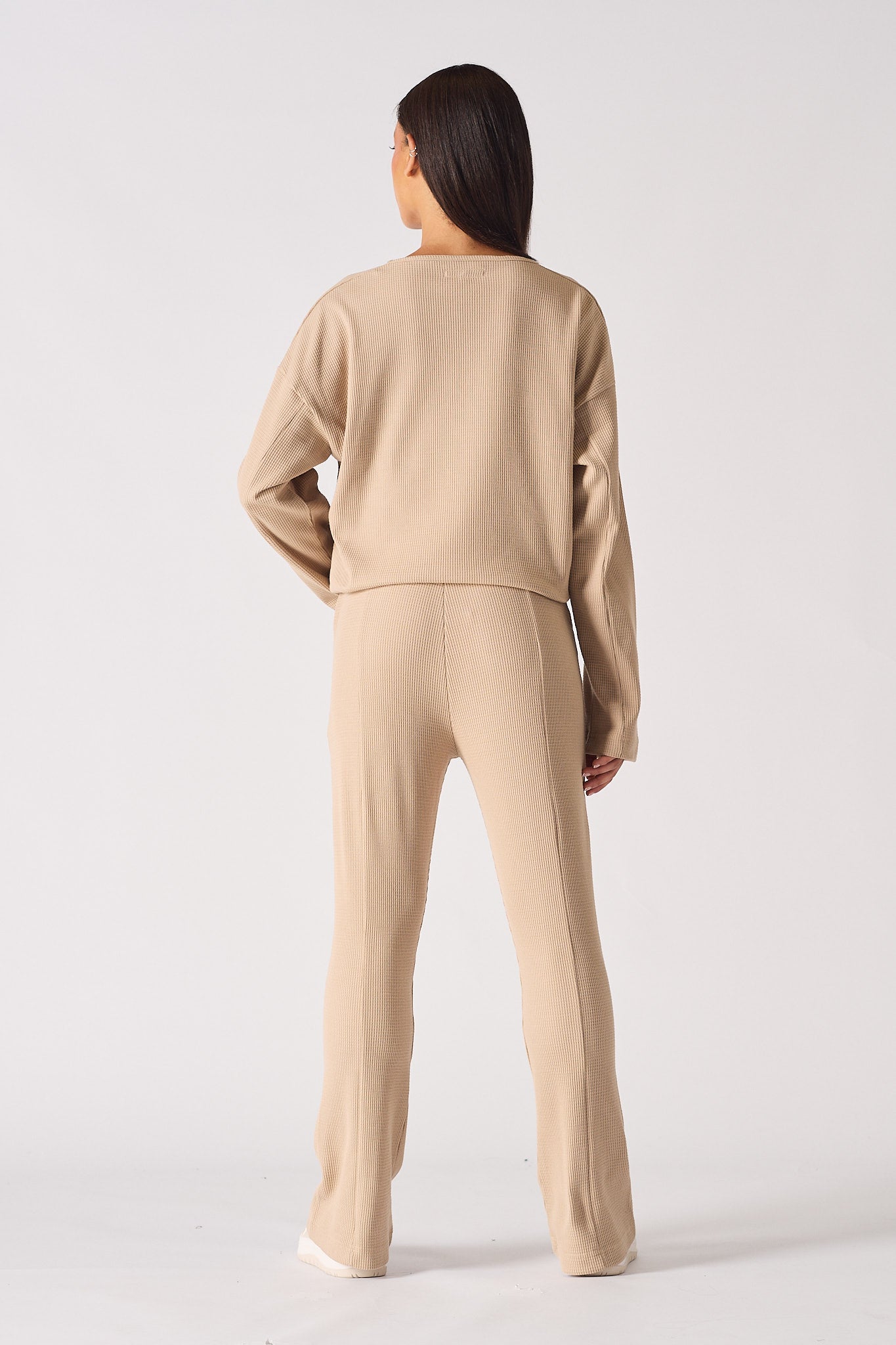 Back view of a model in the beige fit and flare joggers and matching waffle top