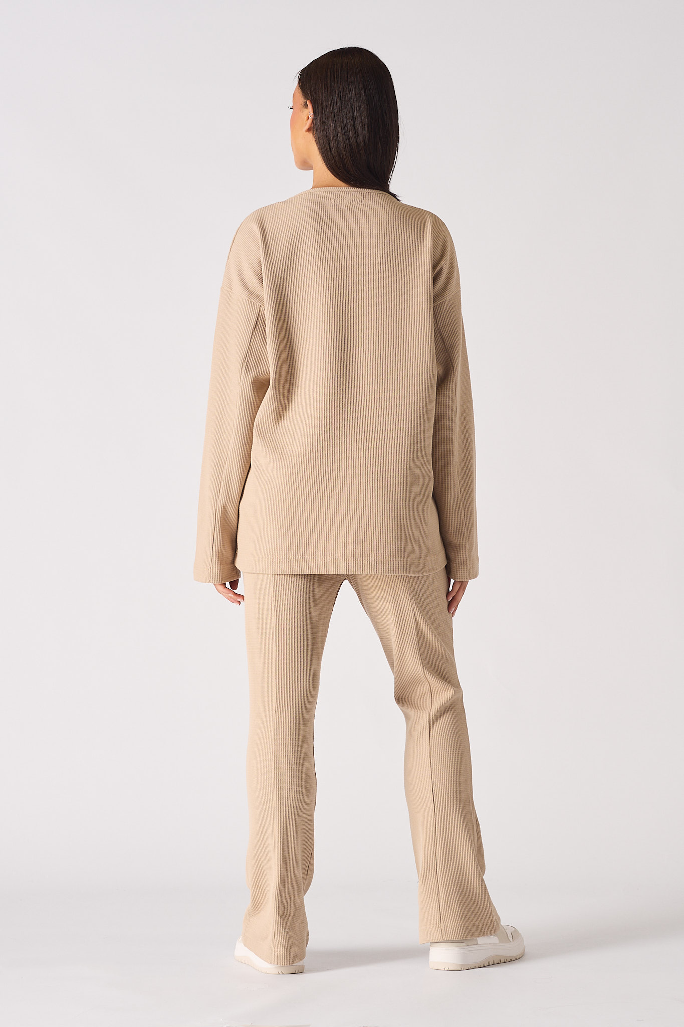 Side profile view showing the oversized fit of the beige v neck jumper