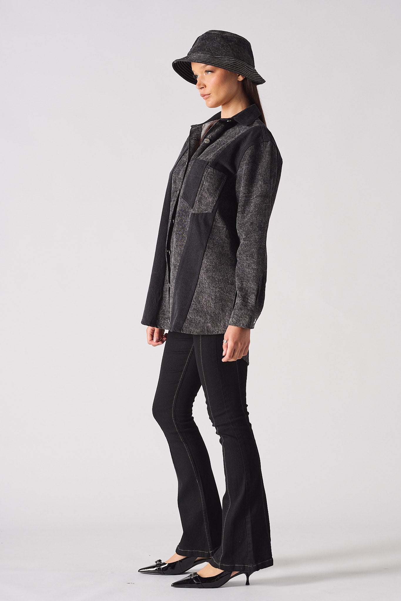 Side profile of a model showing the length of the black acid wash denim shirt.