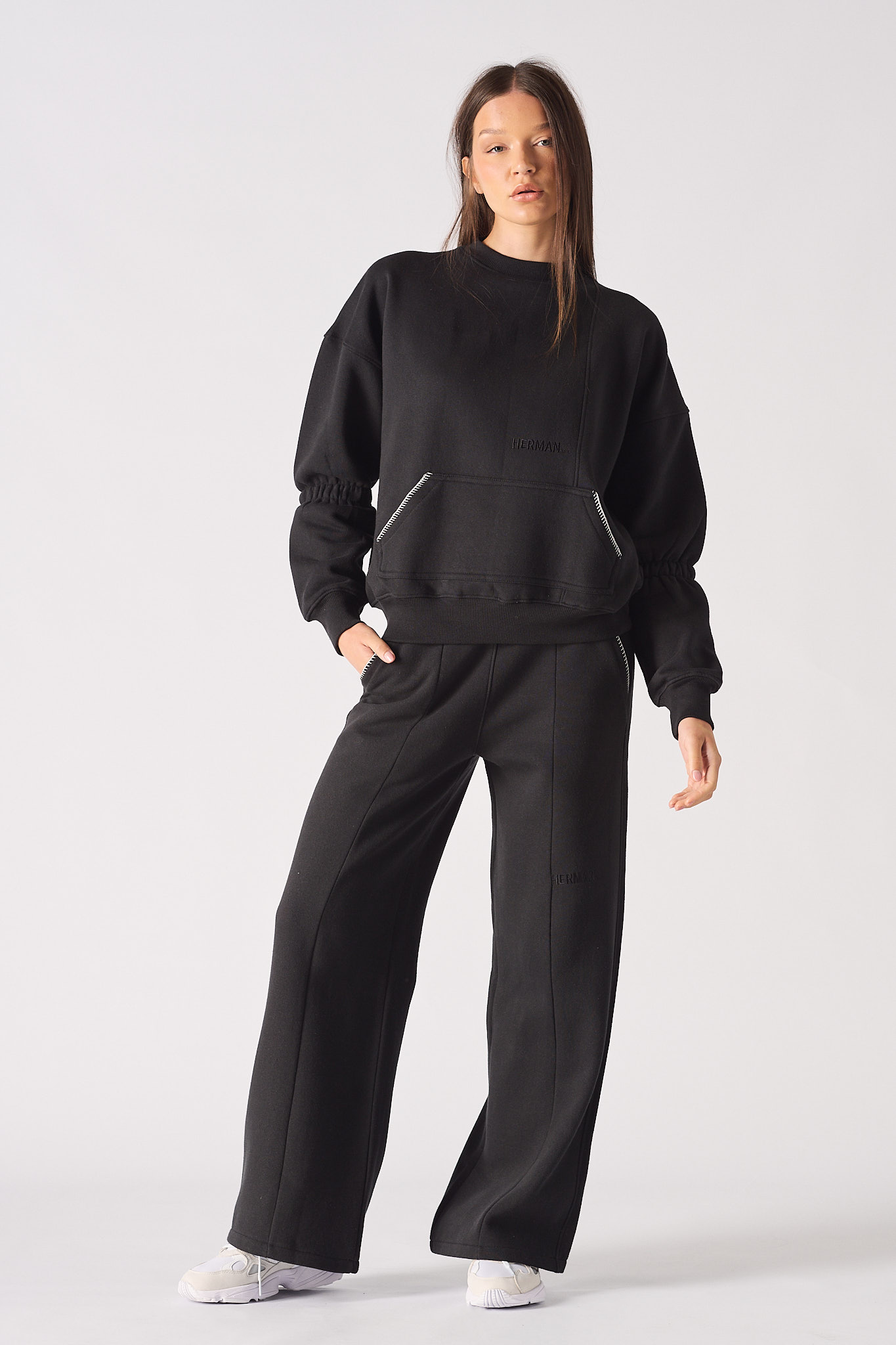 Full front view of a model wearing the black blanket stitch jumper and matching joggers.
