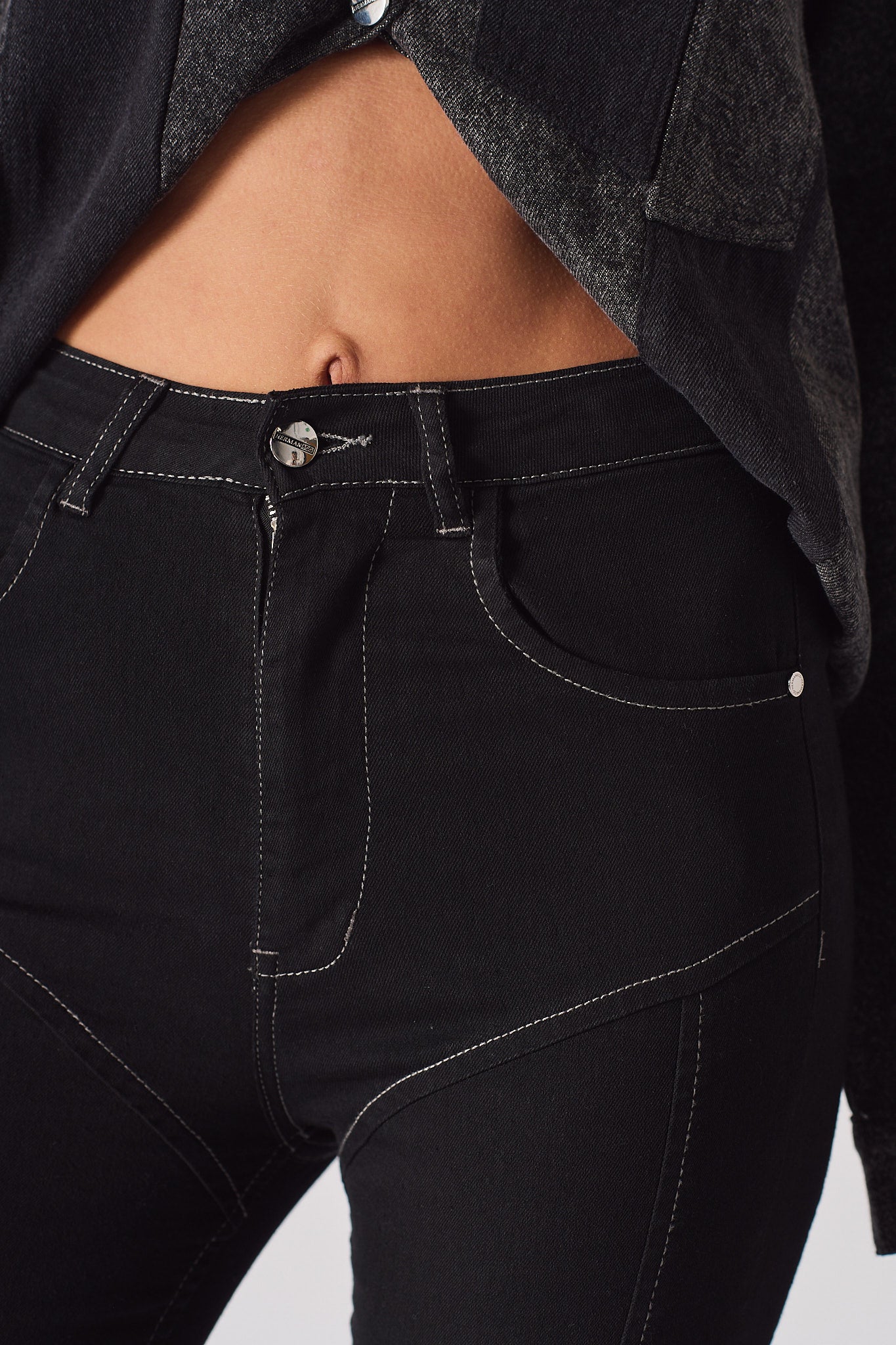Close-up of the white contrast stitch detail on the women's black flare jeans.