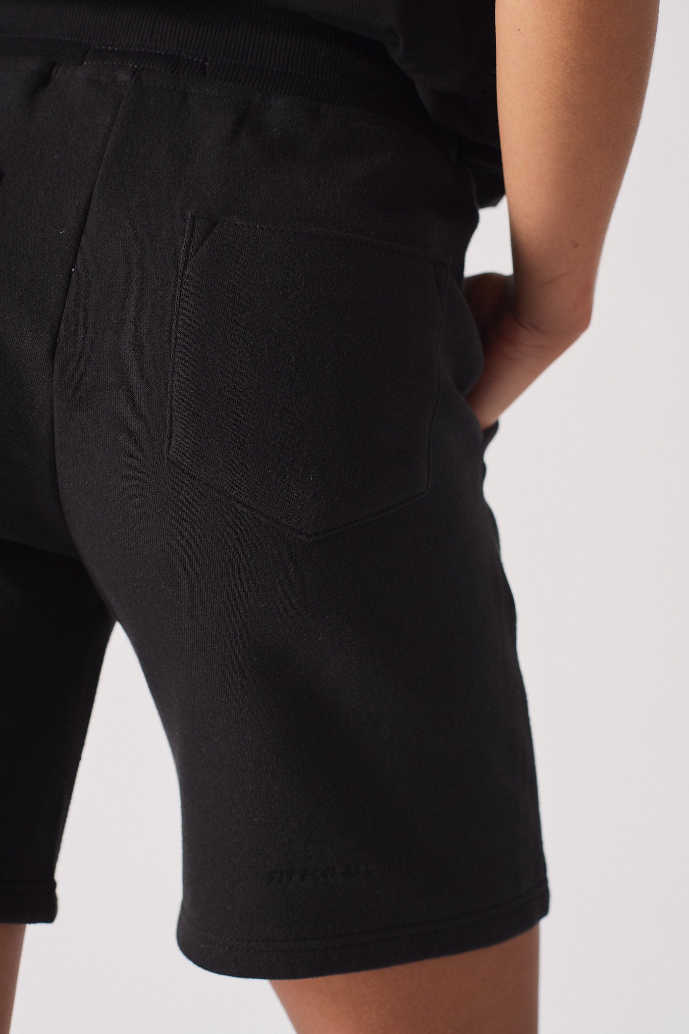 Close up of hand in side pocket of womens black fleece shorts