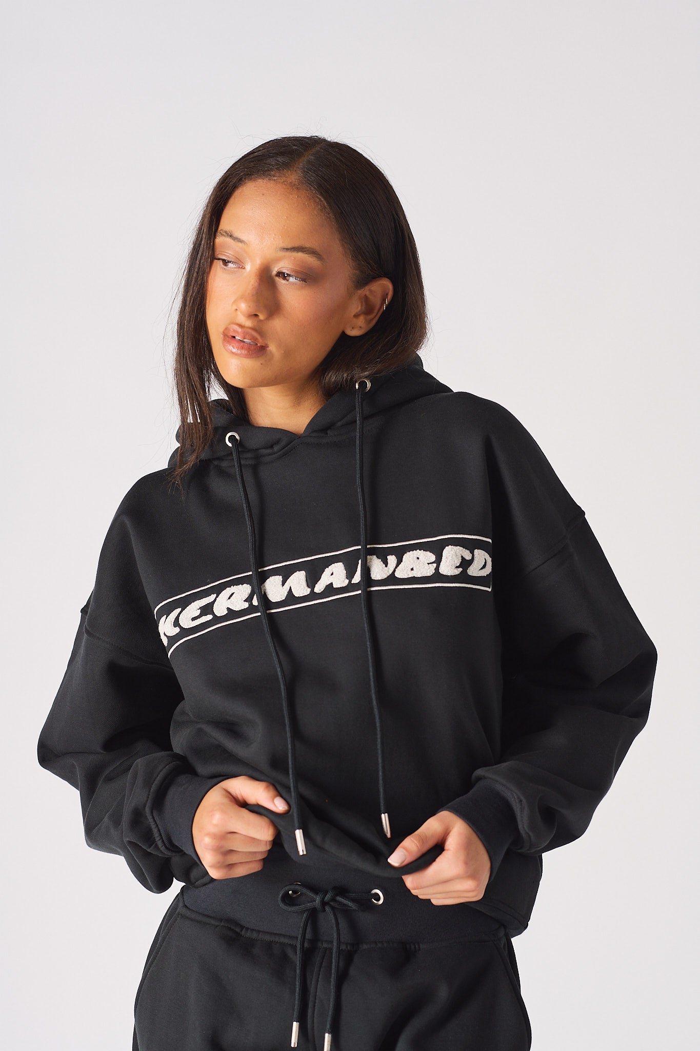 Detailed view of the metal tip drawstrings and logo on black womens hoodie