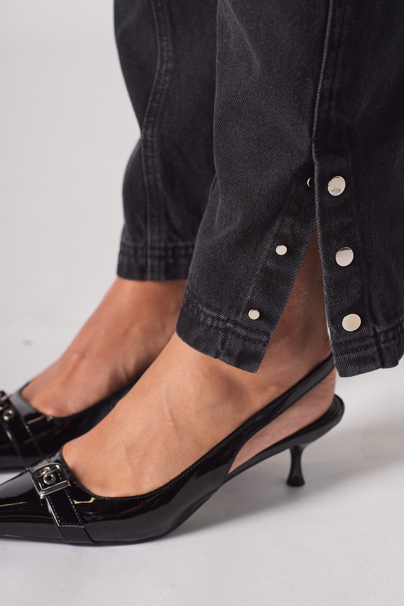 Close-up of the popper button split hem on the black cargo jeans.