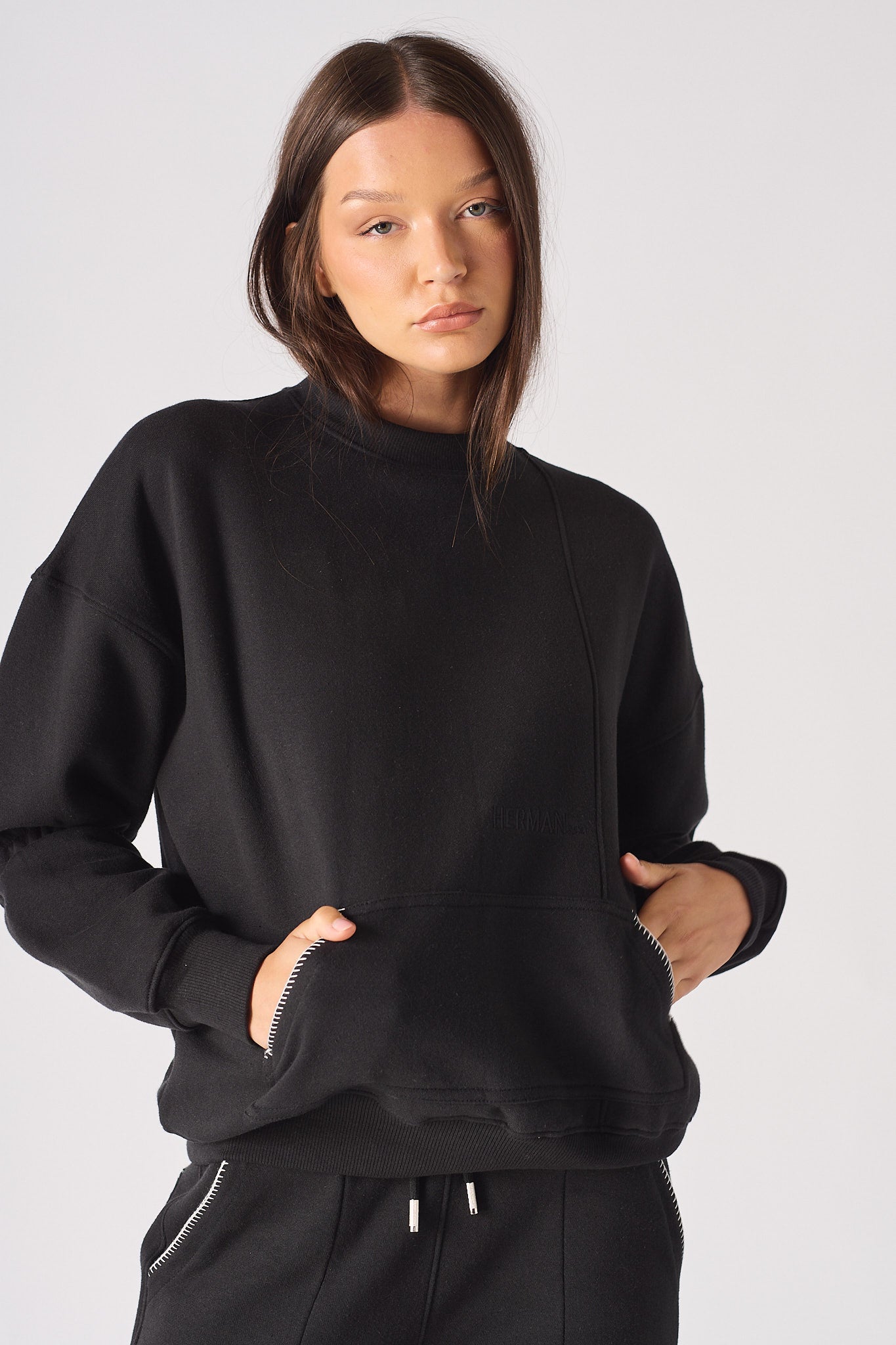 Close-up of a model wearing the black jumper showing the blanket stitch detail.