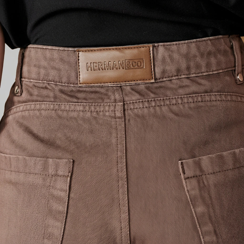 Close-up of the leather logo patch on the back of the brown baggy jeans.