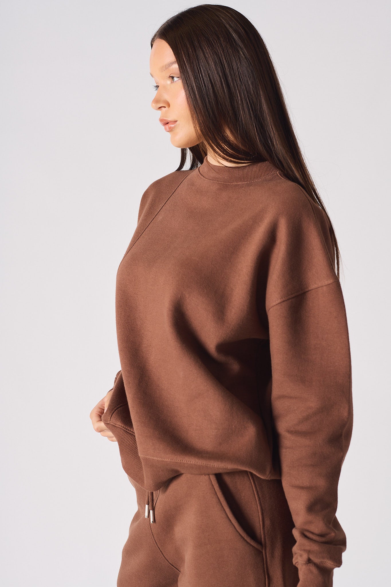 Side profile view of the brown crew neck jumper womens showing the drop shoulder fit