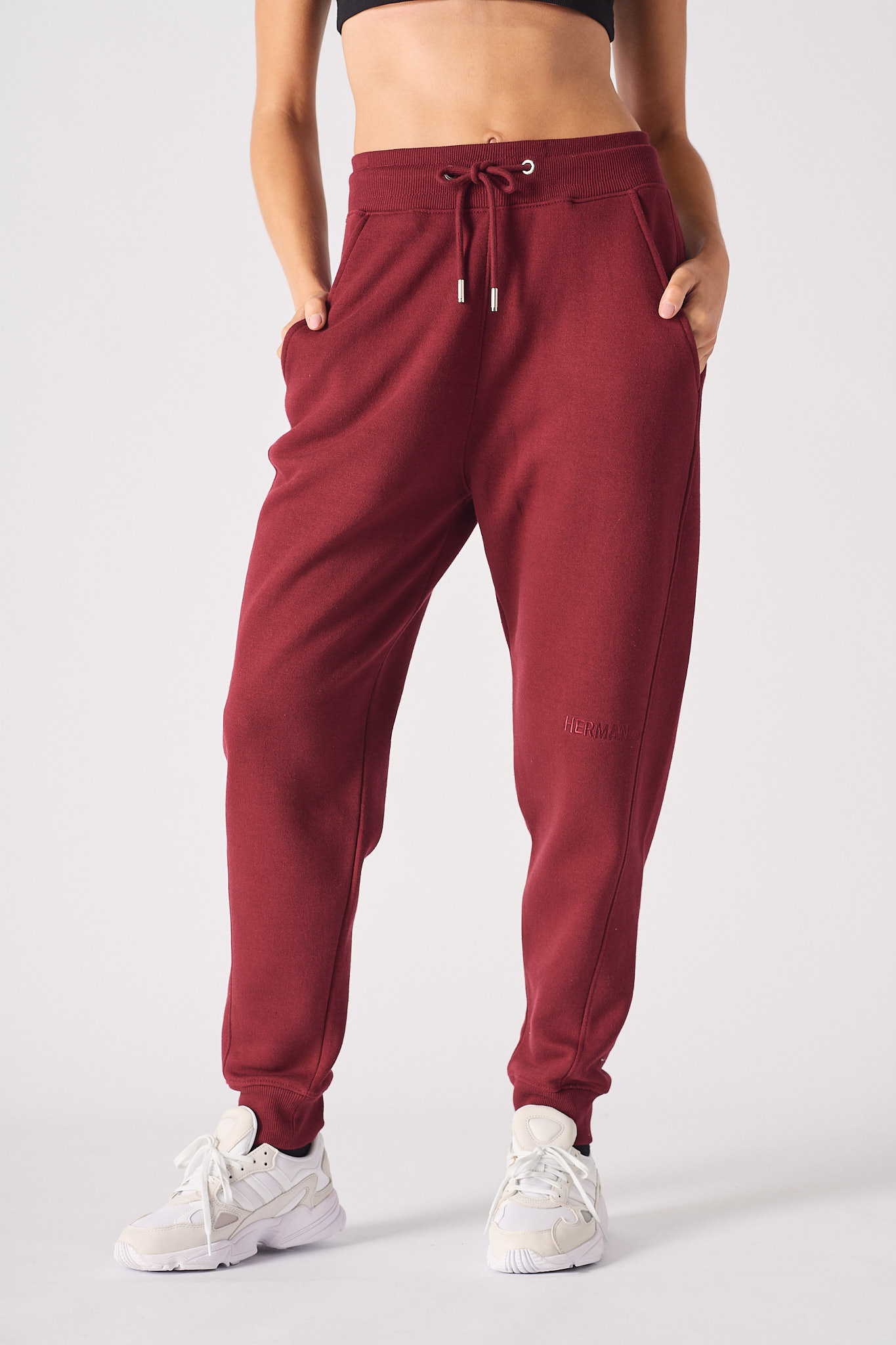 Front view of model wearing burgundy tapered joggers with matching zip up hoodie