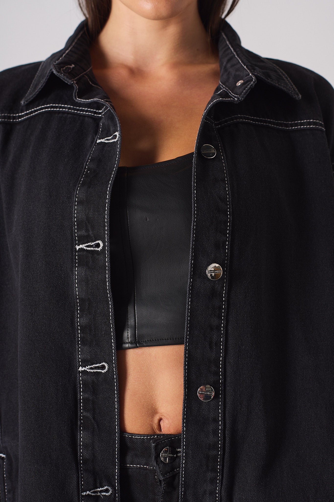 Close-up of the collar and white contrast stitching on the black denim shirt.