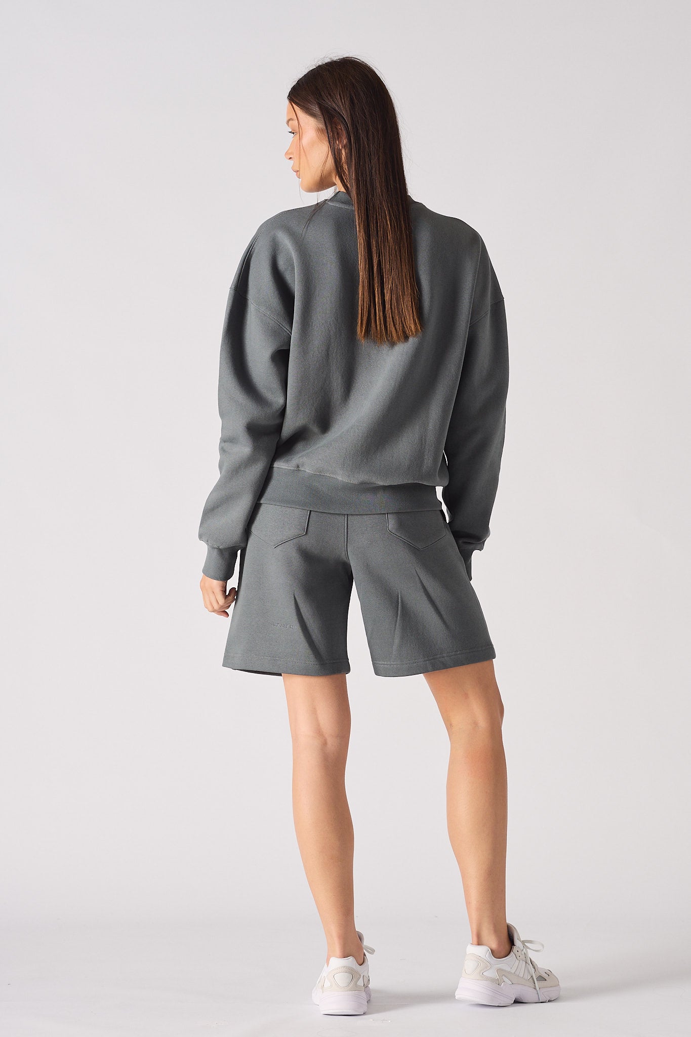 Rear full body view of model wearing cool grey crew neck jumper