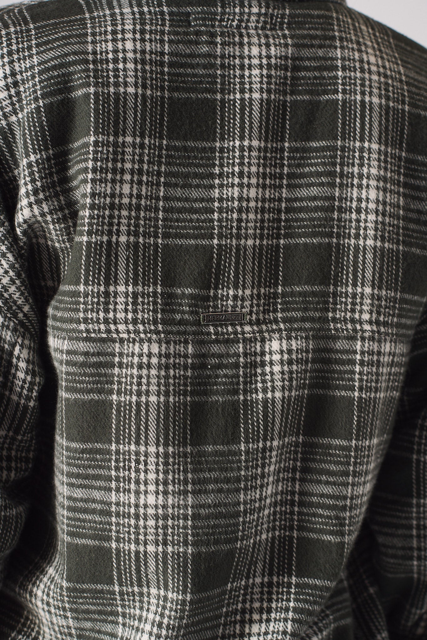 Close-up of the dark green and white check pattern on the women's shirt.