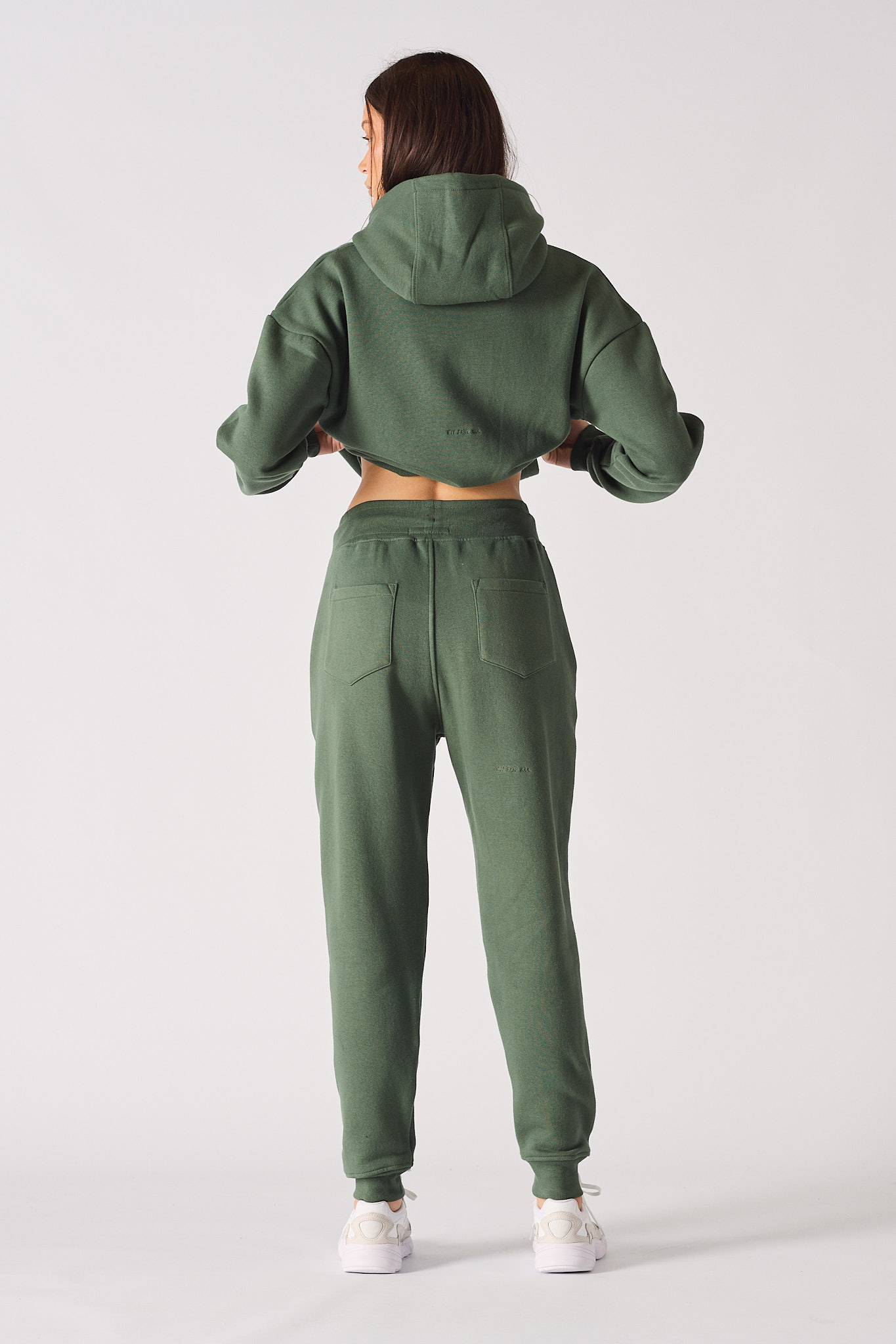 Back view of a model in the women's dark green tracksuit with tapered joggers.