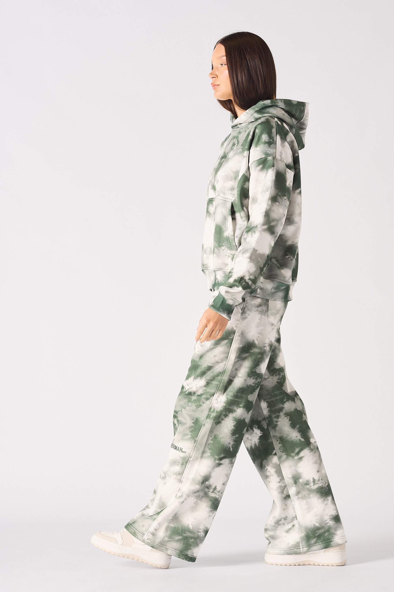 Side profile of model walking in a dark green tie dye hoodie womens outfit