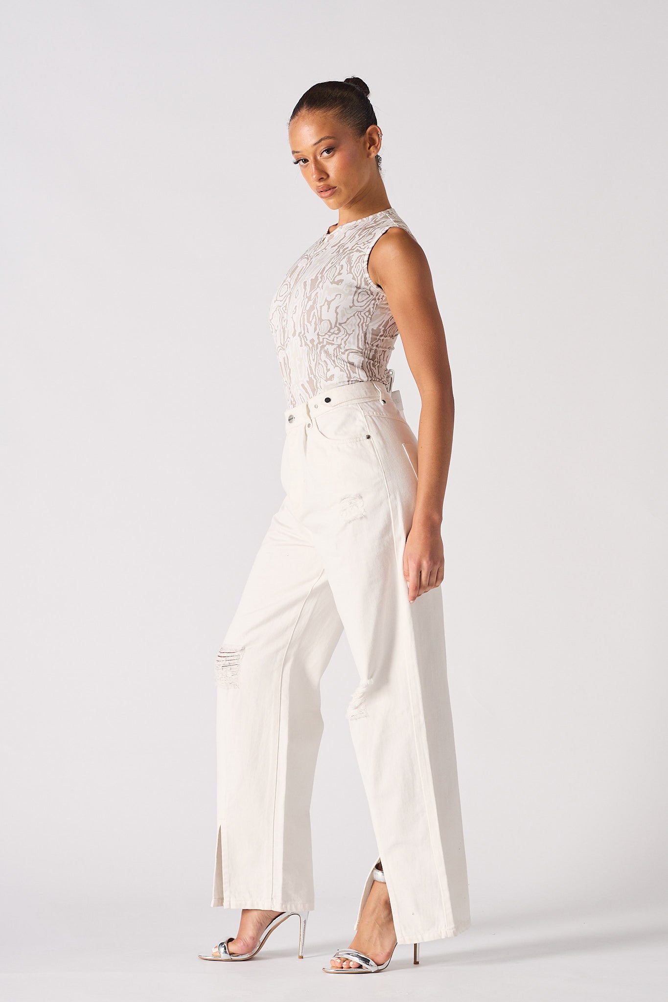 Side profile of a model showing the fit of the distressed white baggy jeans.