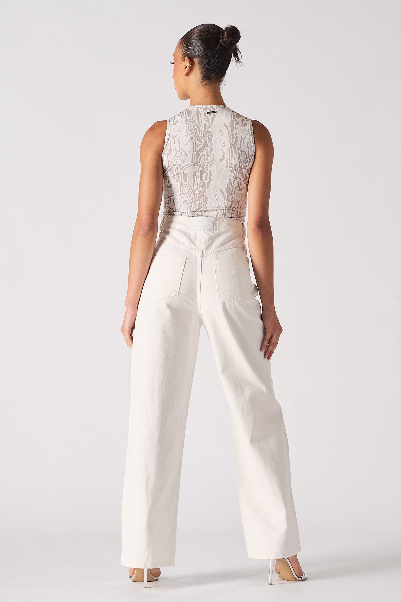 Back view of a model wearing the distressed white jeans for women.