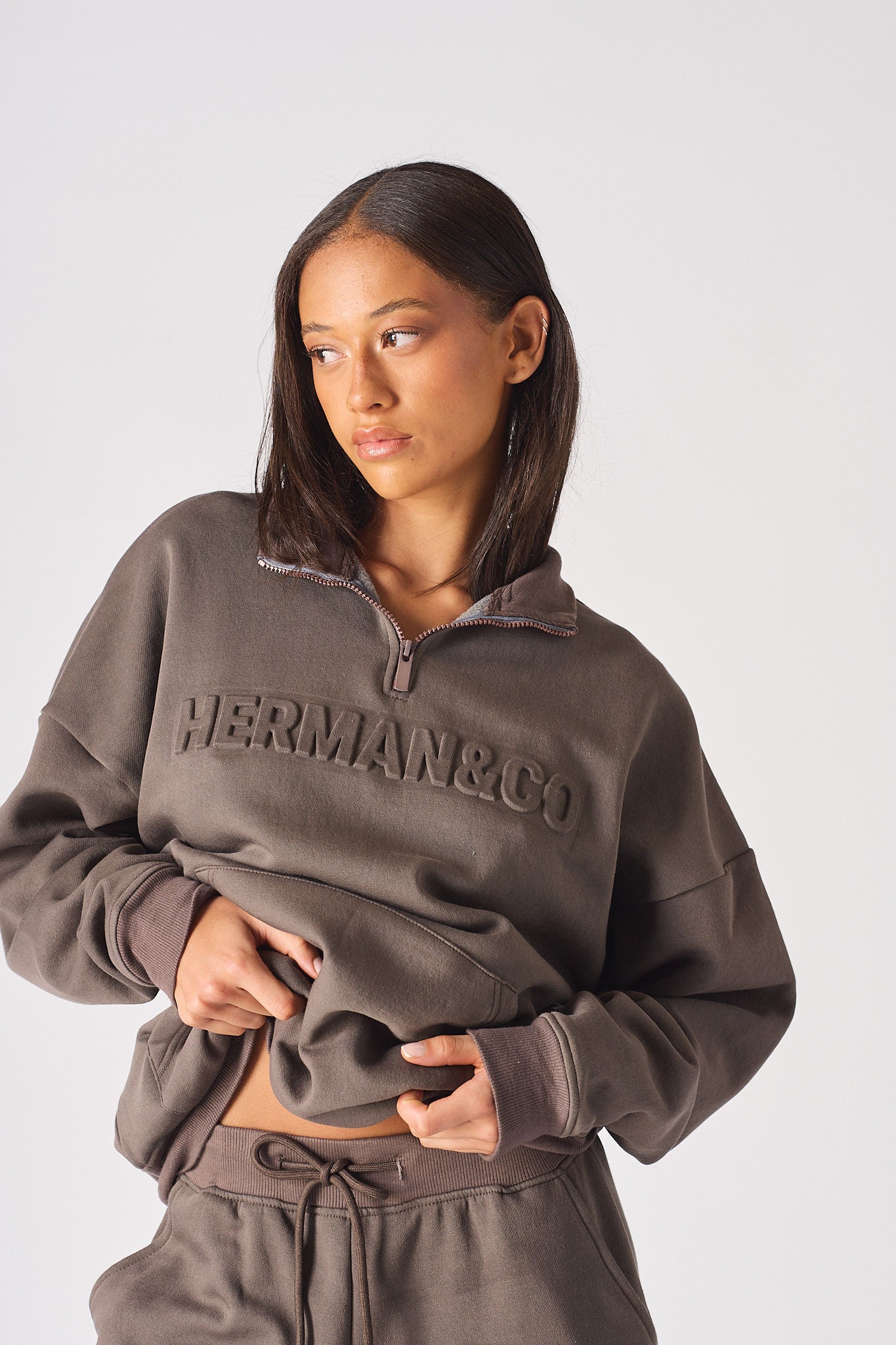 Close up of the embossed chest logo on brown half zip women's sweatshirt