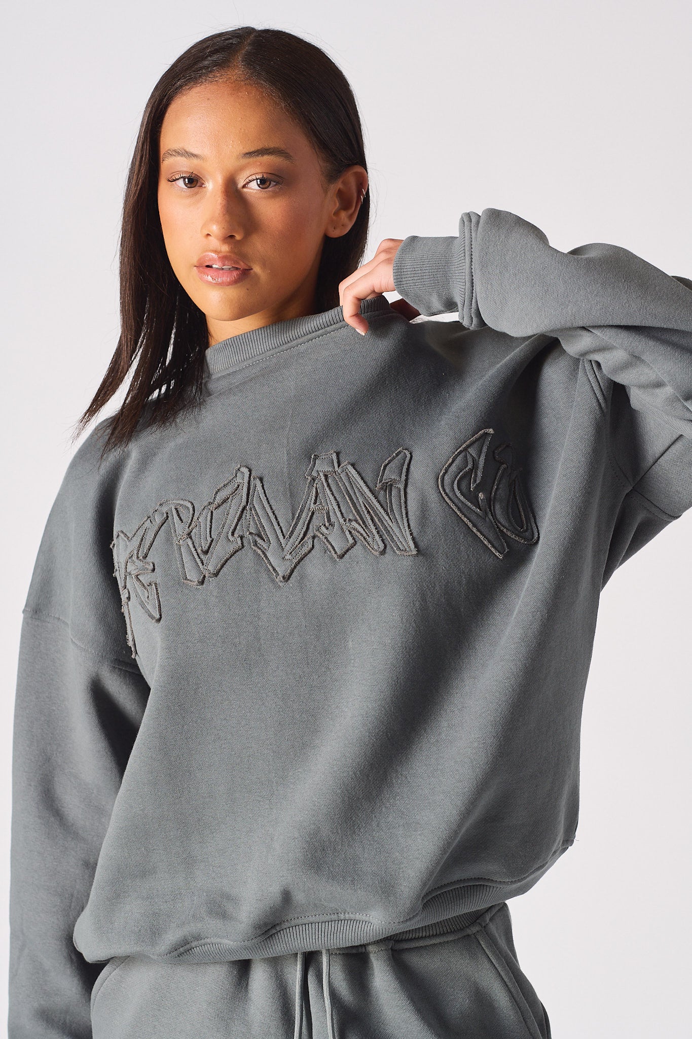 Close up detail of the embossed HERMAN logo on the chest of womens grey sweatshirt