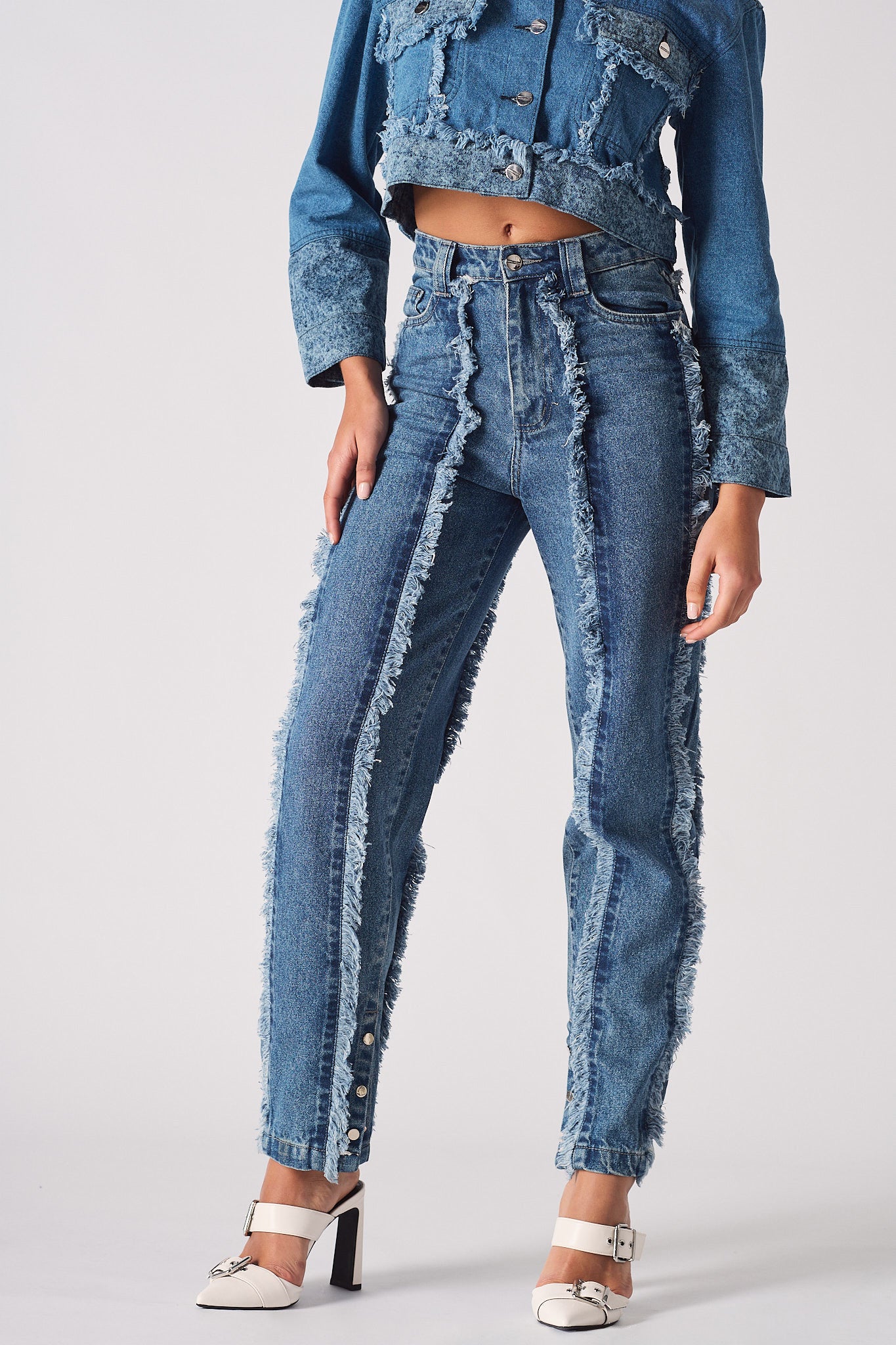 Close-up of the frayed seam and distressed details on the blue straight leg jeans.