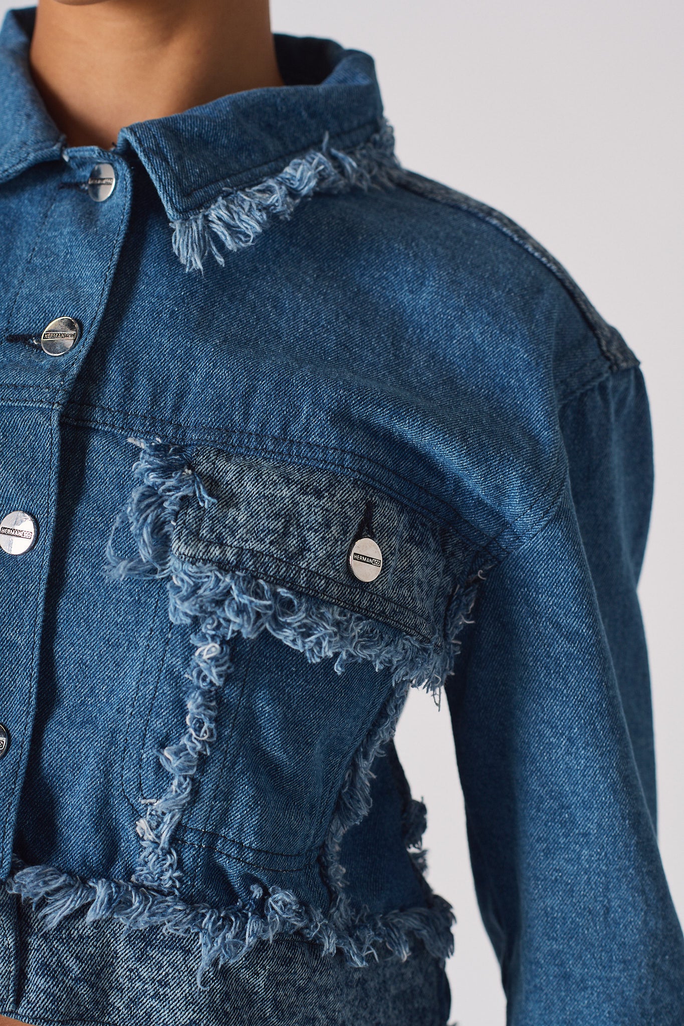 Close-up of the frayed pocket detail on the two-tone denim jacket.