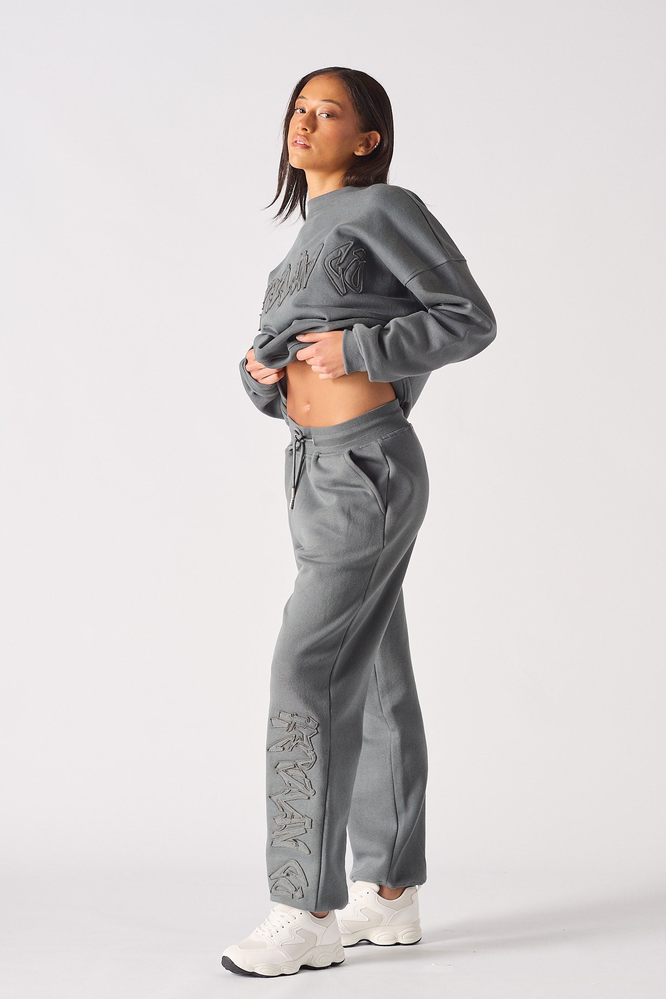 Side profile of a model showing the fit of the grey cuffed joggers for women.