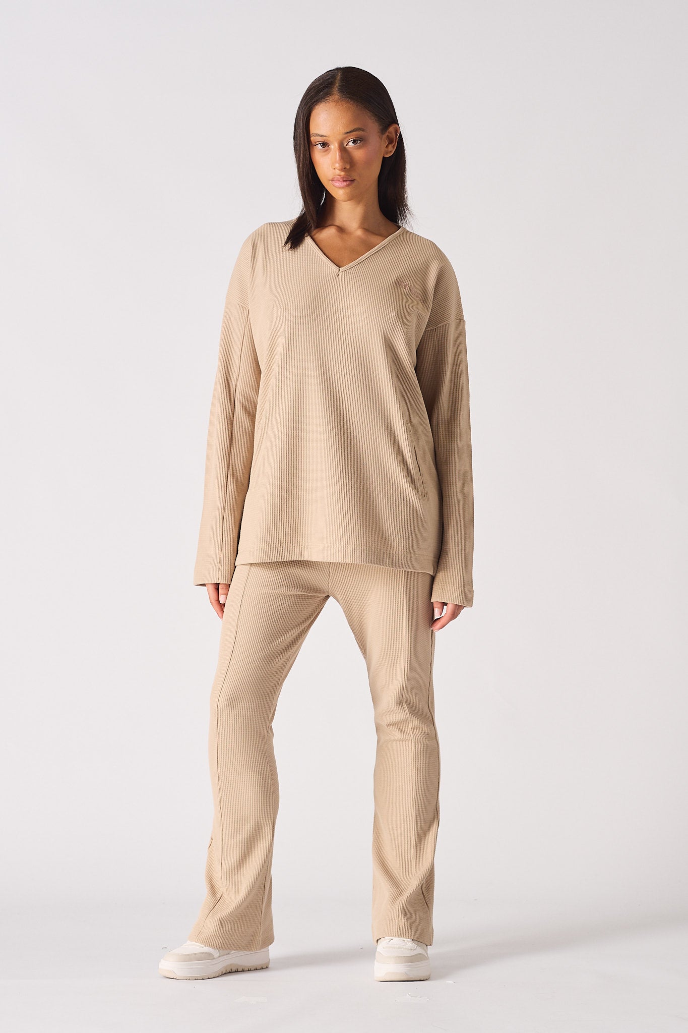 Model looking at the camera wearing the Herman & Co beige waffle flare joggers set
