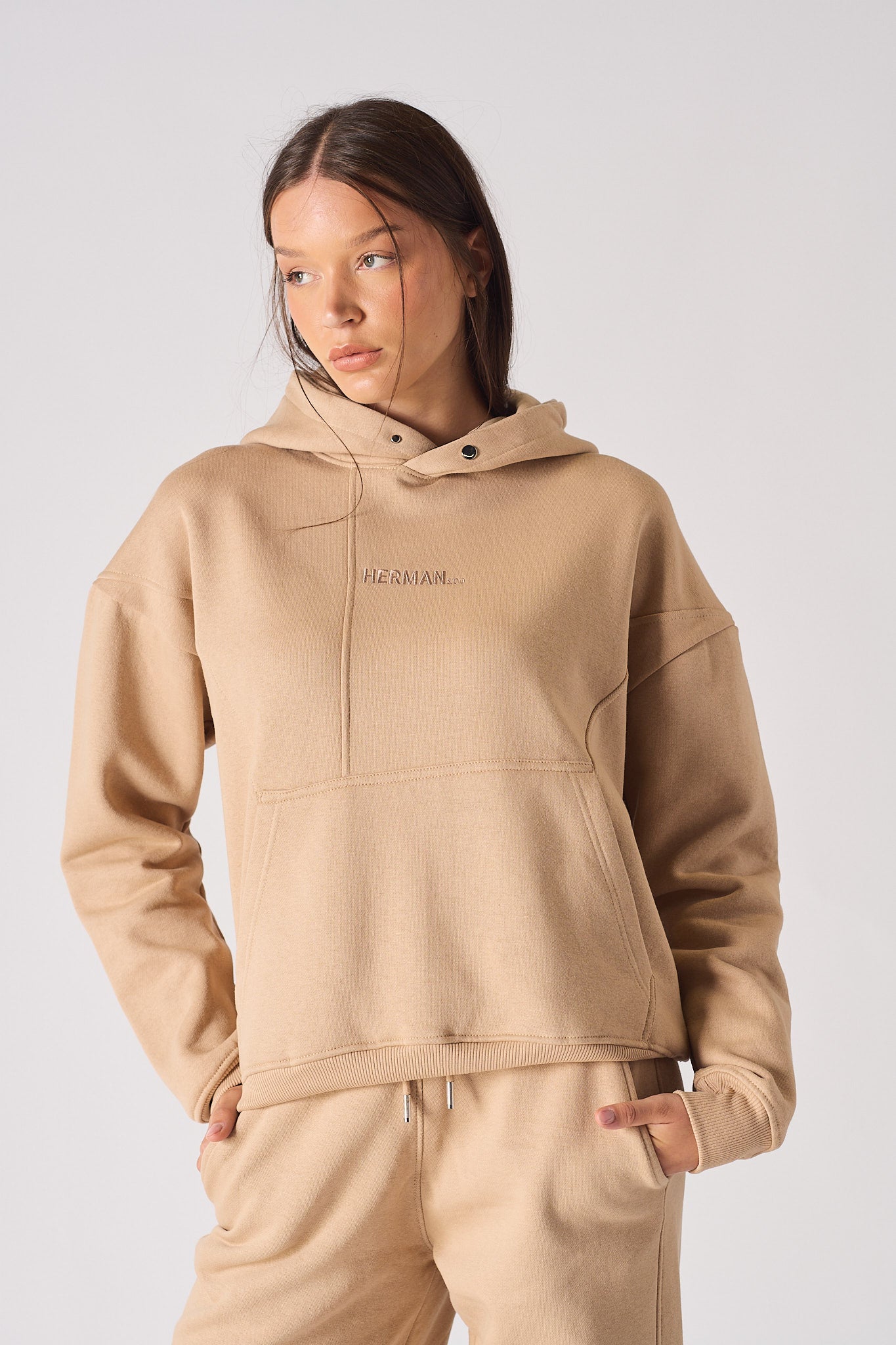 Detailed view of the tonal logo embroidery on the chest of womens beige hoodie