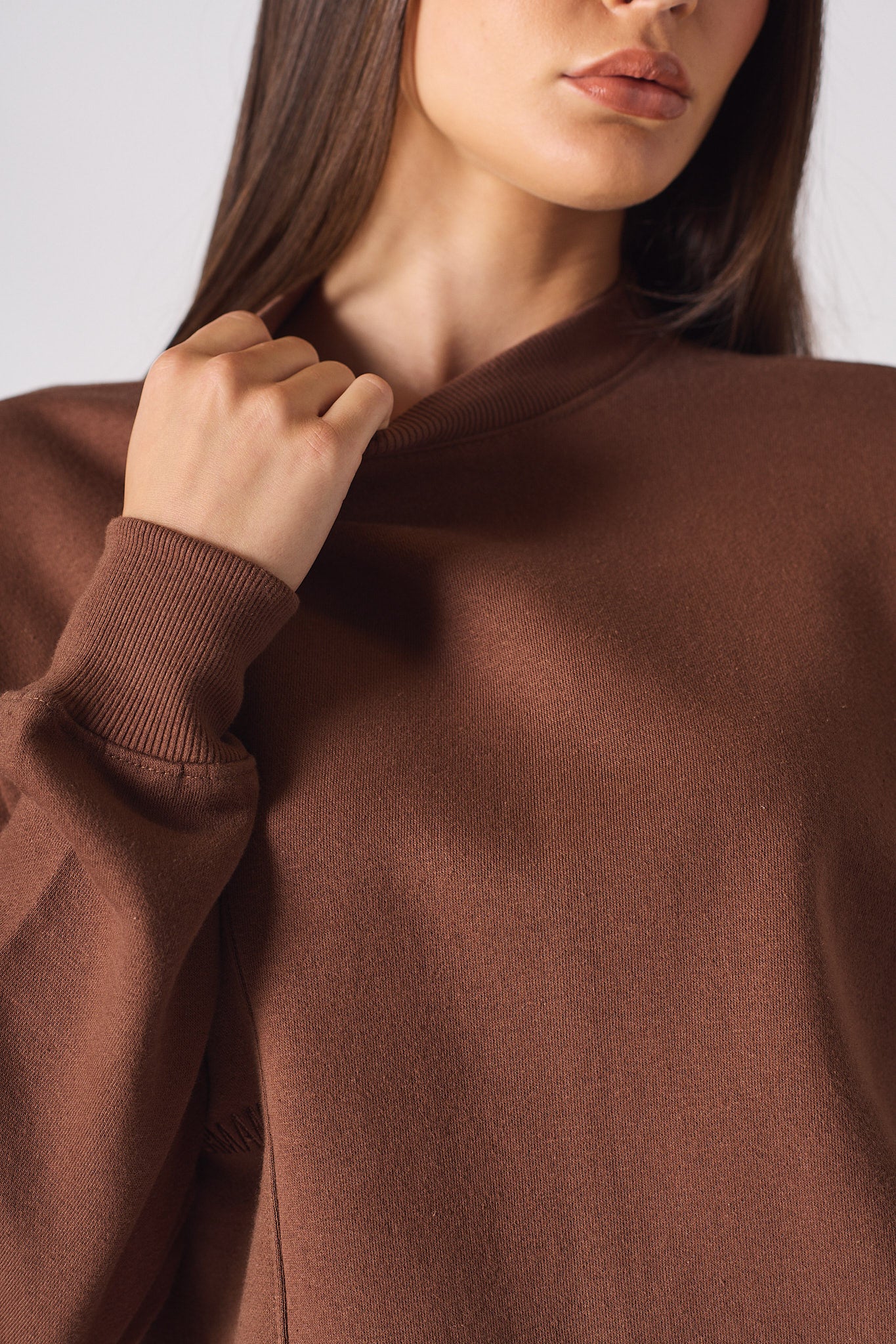 Detail of the tonal logo embroidery on the chest of brown crew neck jumper