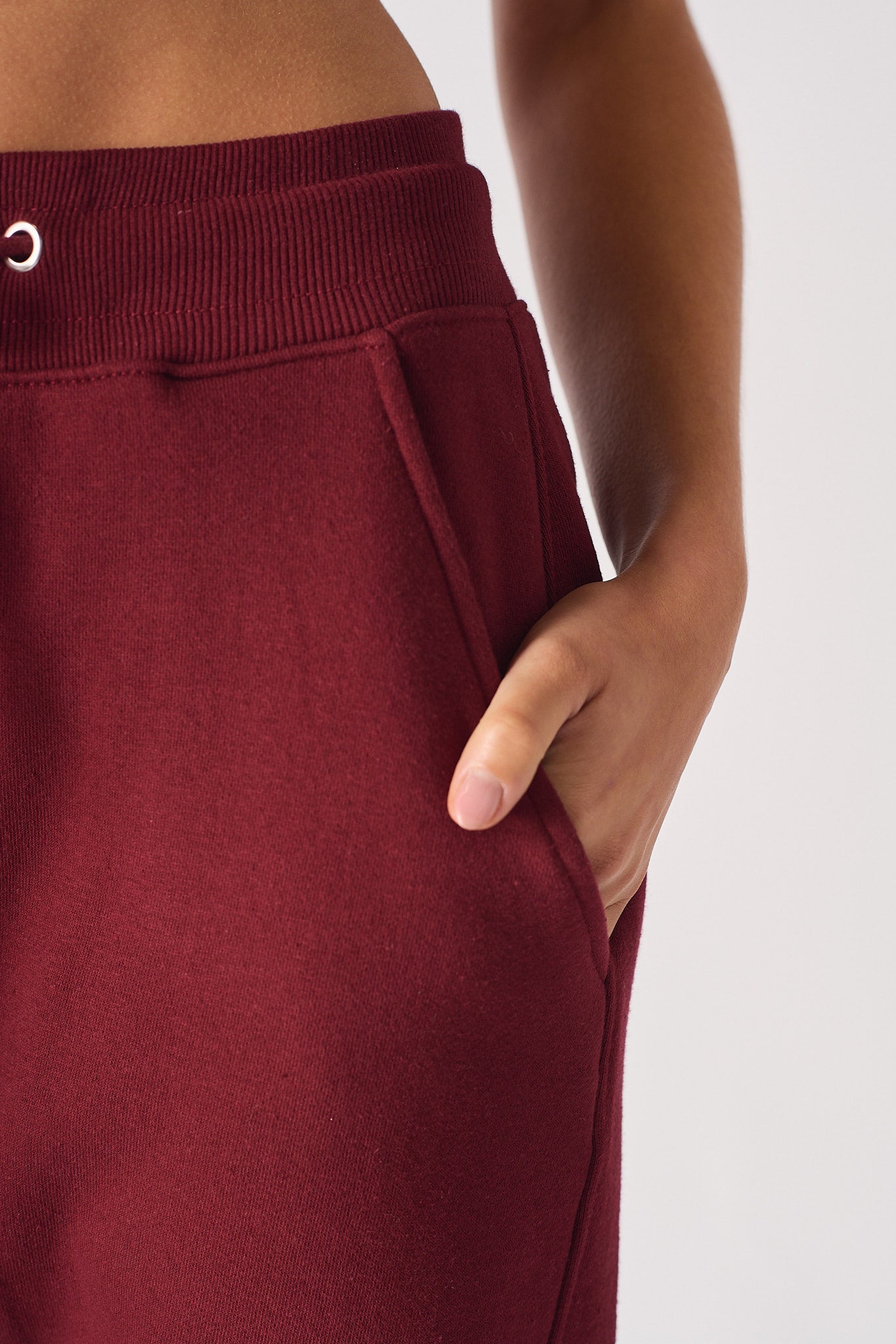 Detail of the tonal logo embroidery on the leg of burgundy tapered joggers