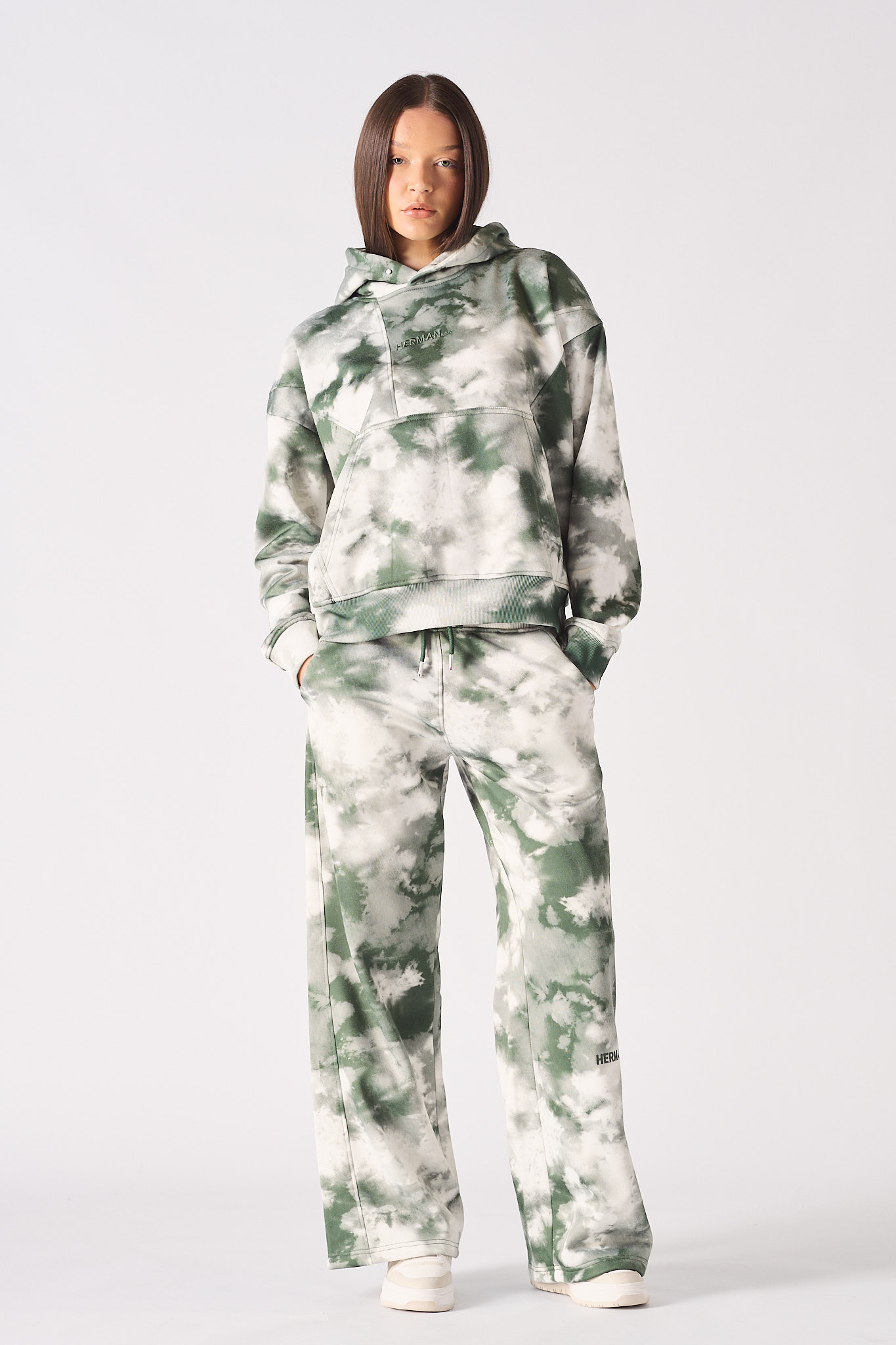 Detailed close up of the HERMAN logo embroidery on chest of green tie dye hoodie