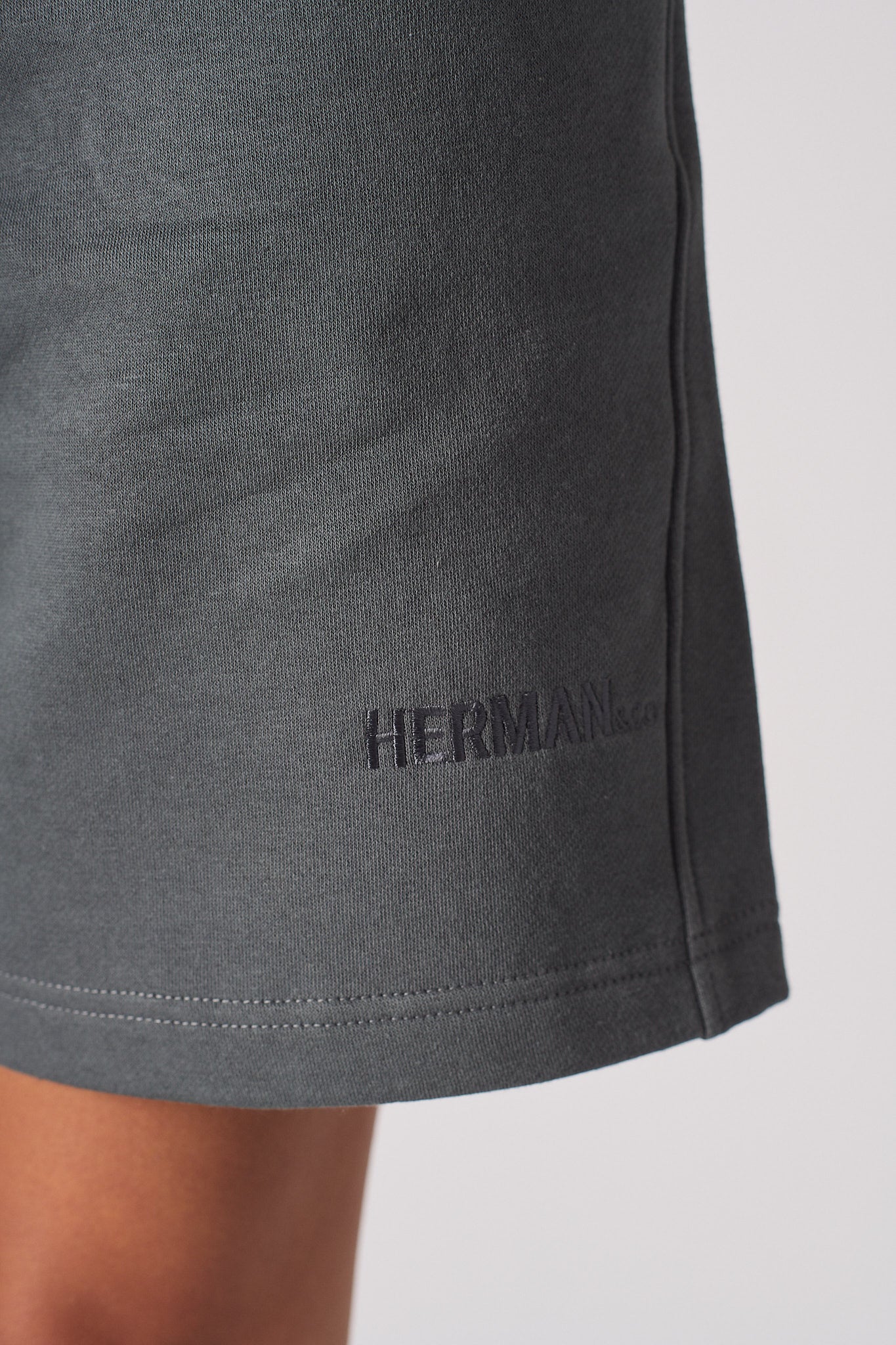 Close up of HERMAN logo embroidery near the hem of womens shorts