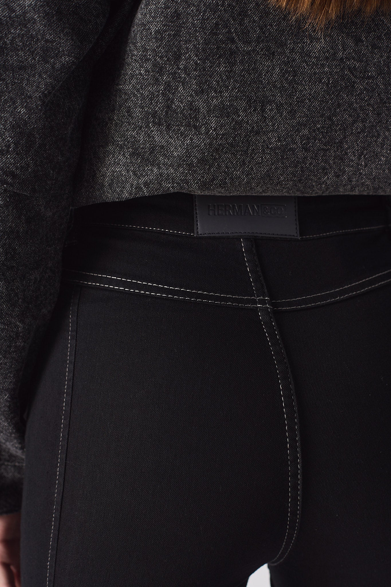 Close-up of the back pockets and logo patch on the high-rise black flare jeans.