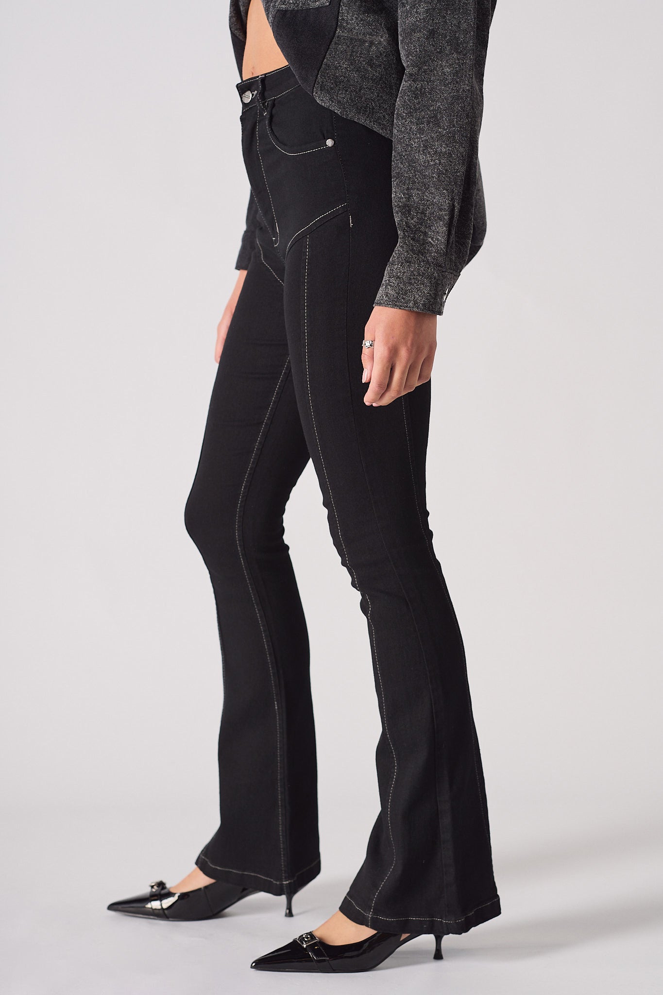 Side profile of a model showing the fit of the high-rise flare jeans in black.