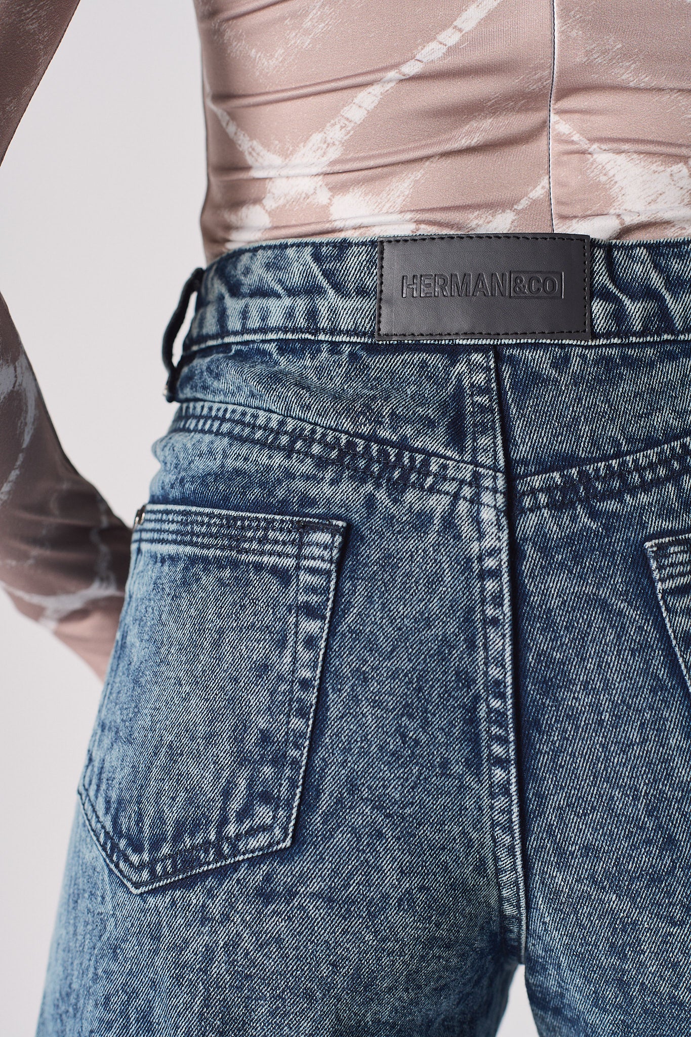 Close-up of the back pockets and high-waisted fit on the acid wash mom jeans.