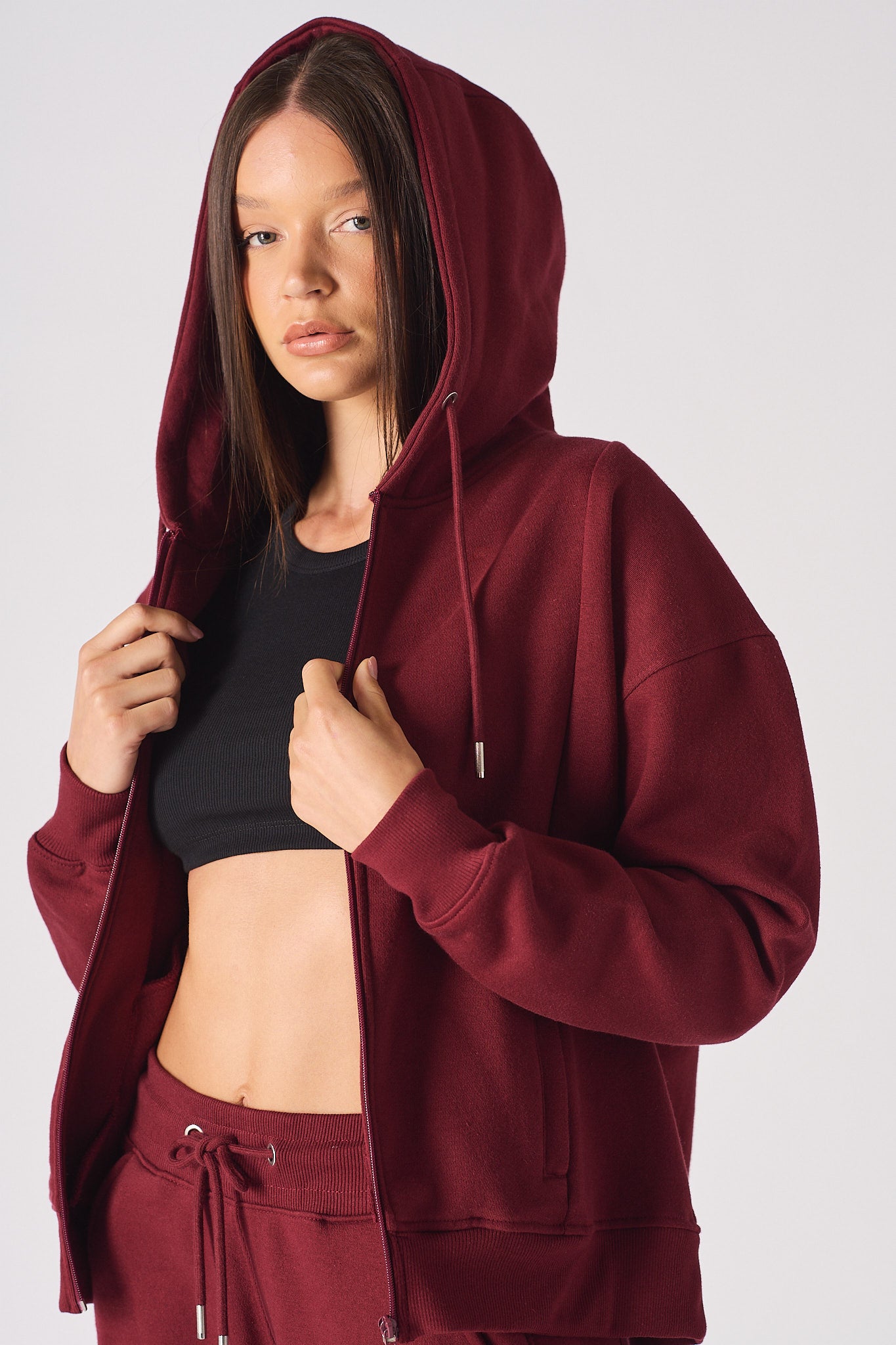 A model wearing the ladies' red zip-up hoodie with the hood up.