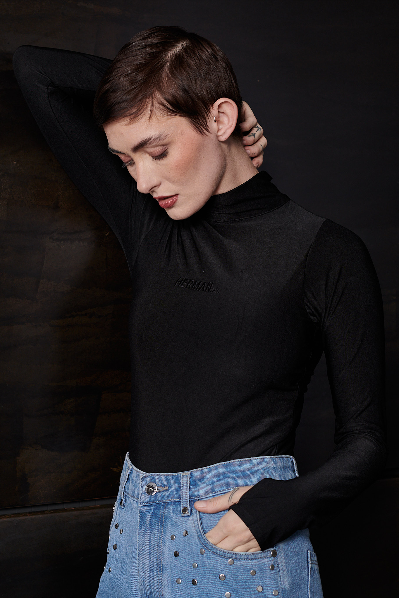 A model posing in the long-sleeve spandex bodysuit in black.