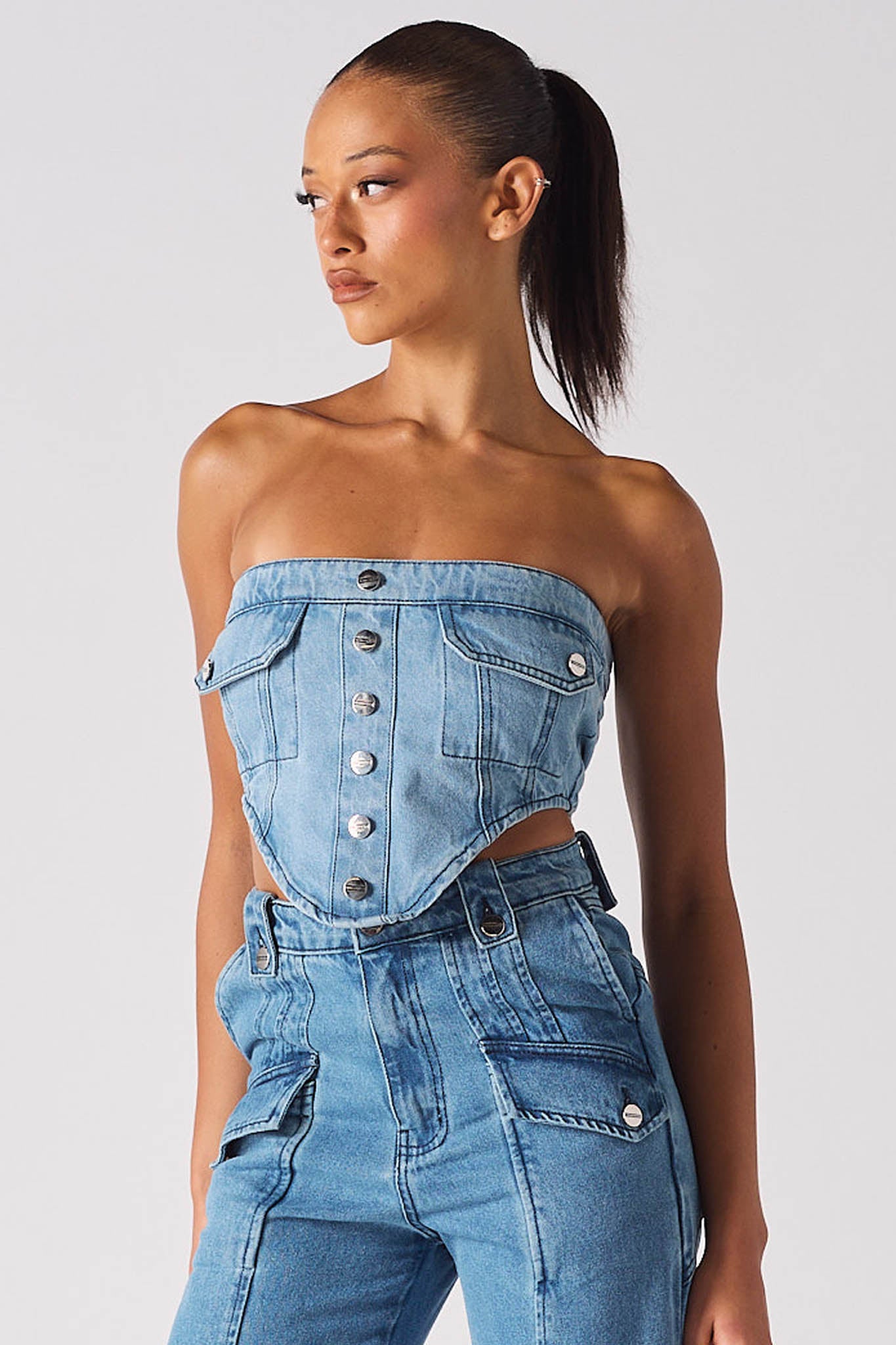 A model styled in the strapless light blue wash denim corset with matching jeans.