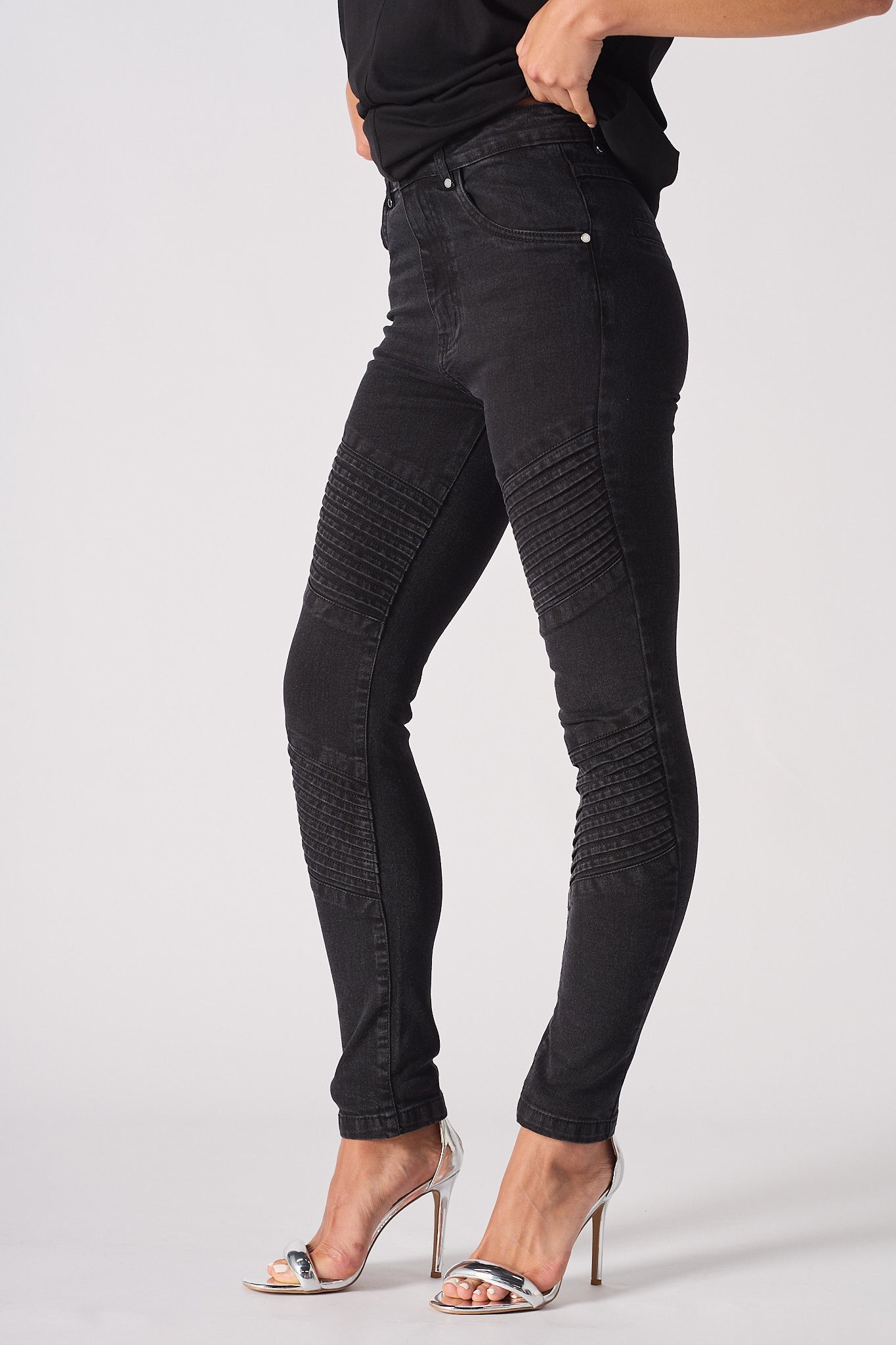 Side profile of a model showing the fit of the women's black skinny biker jeans.