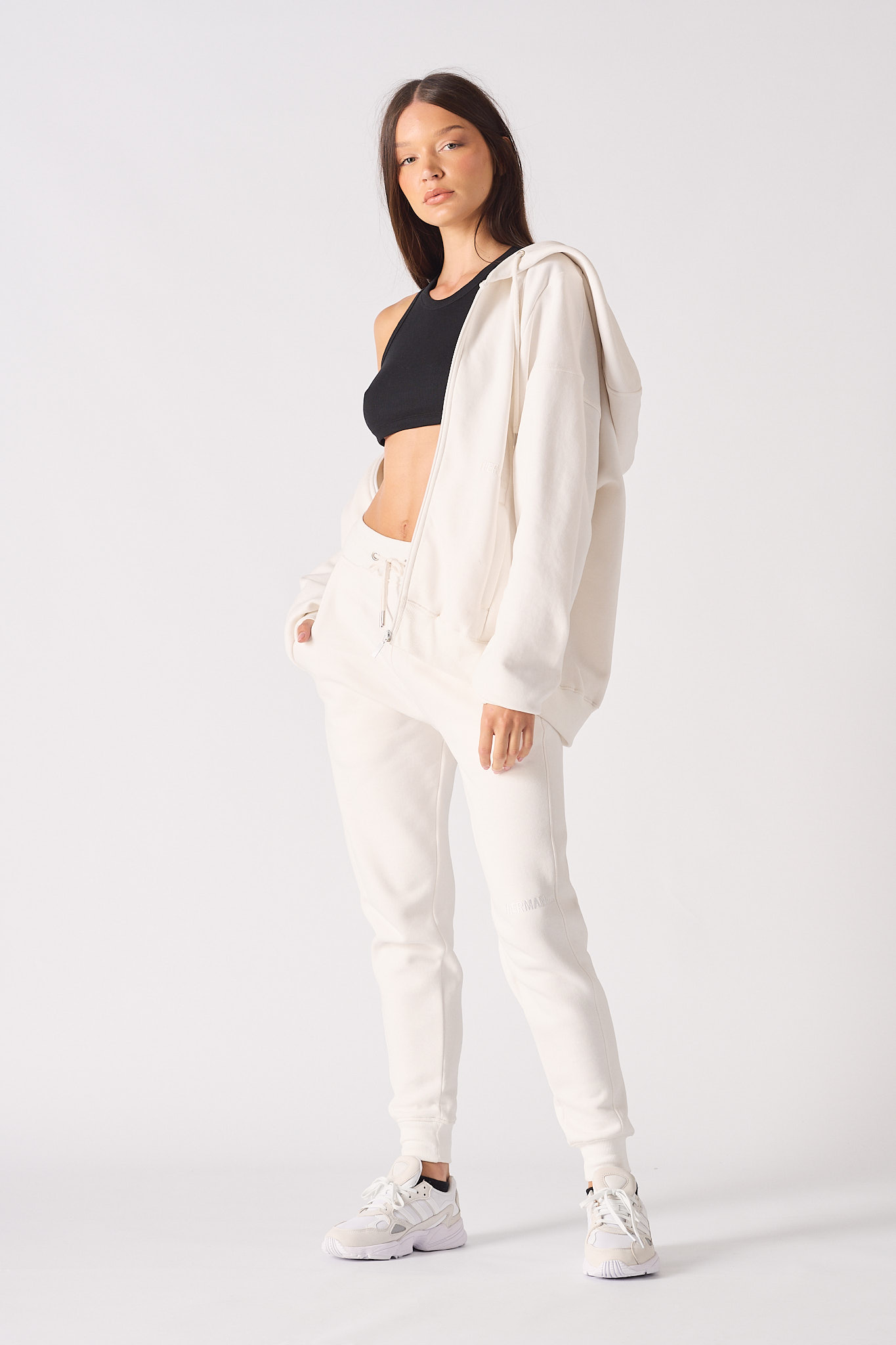 A model styled in the women's white zip-up hoodie, worn open.