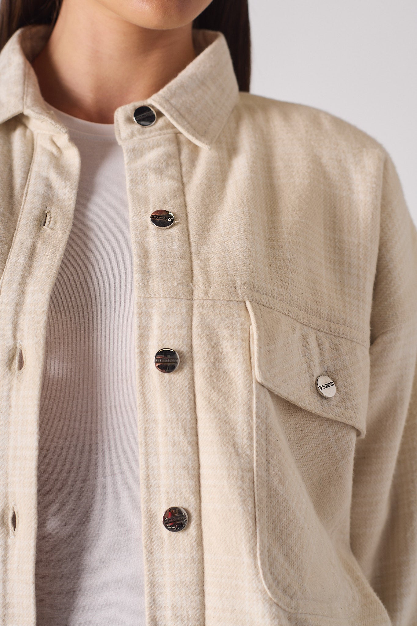Close-up of the button front and pocket on the women's beige check shirt.