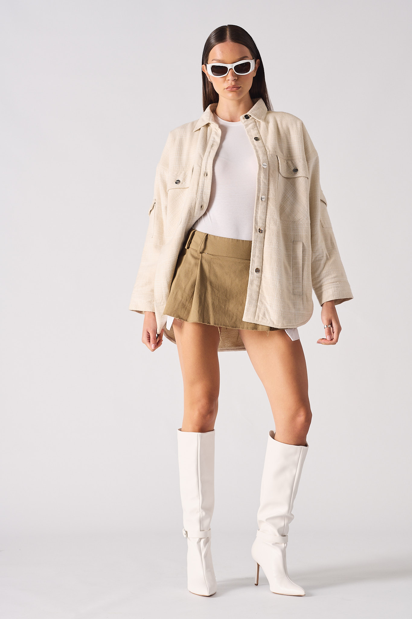 A model styled in the women's beige checked overshirt with a skirt and boots.