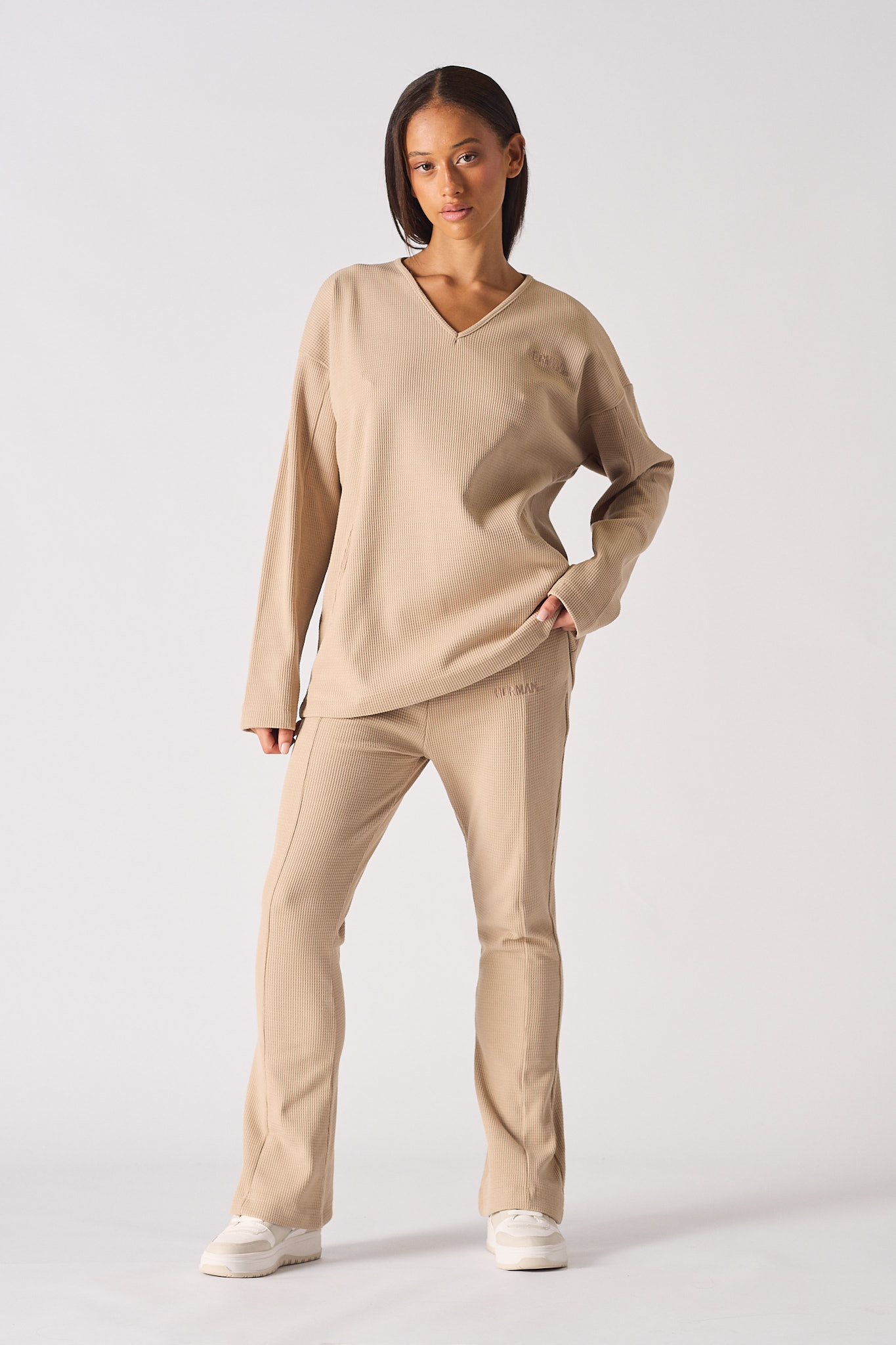 Close up view of the ribbed v neckline on womens beige jumper