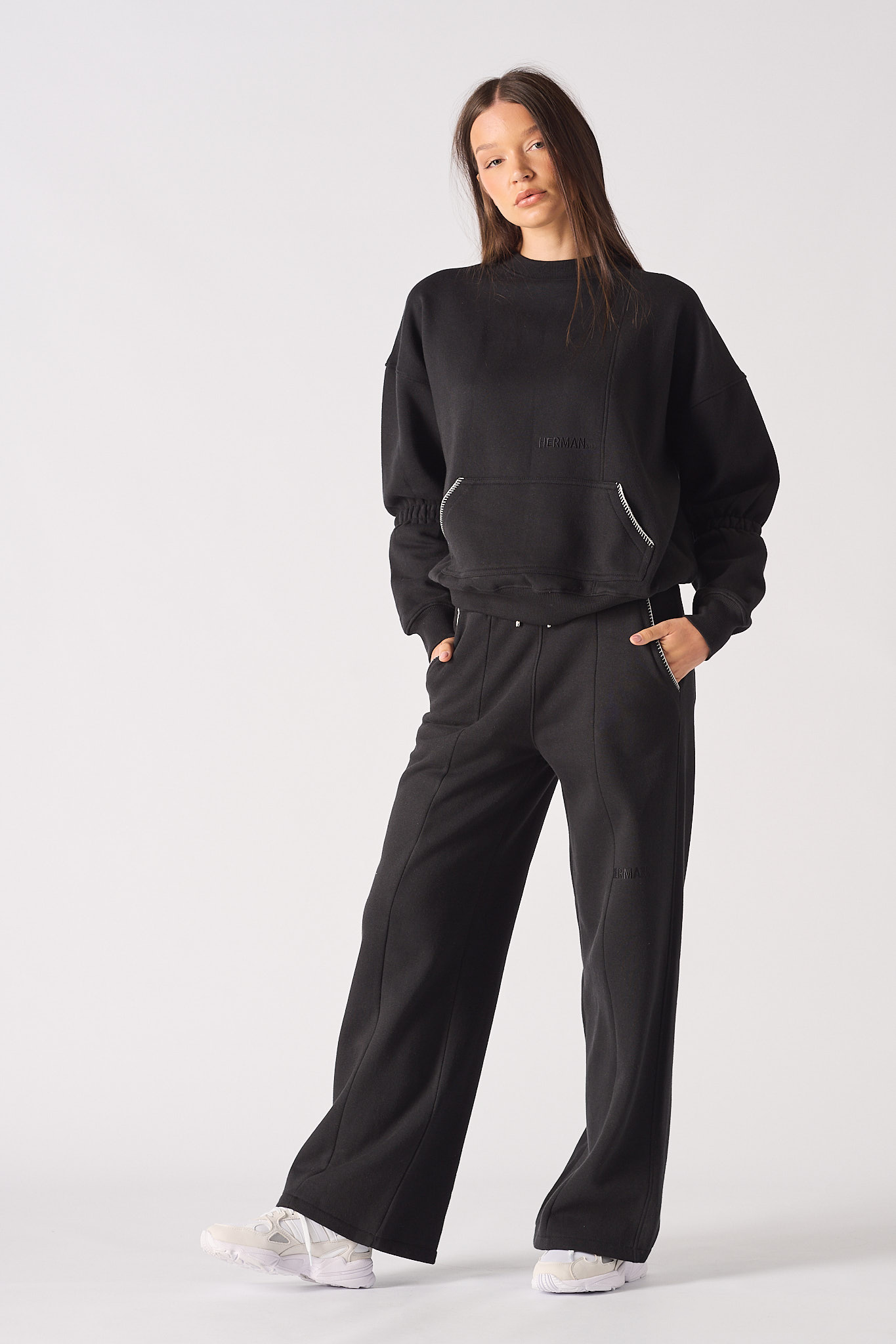 A model styled in the women's black jumper with blanket stitch detail.