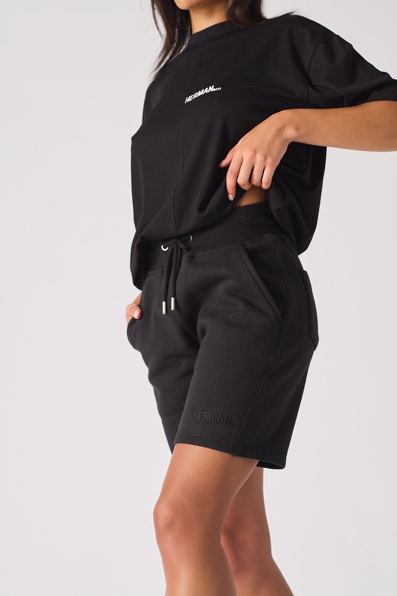 Front view of model styled in womens black fleece shorts and matching tee