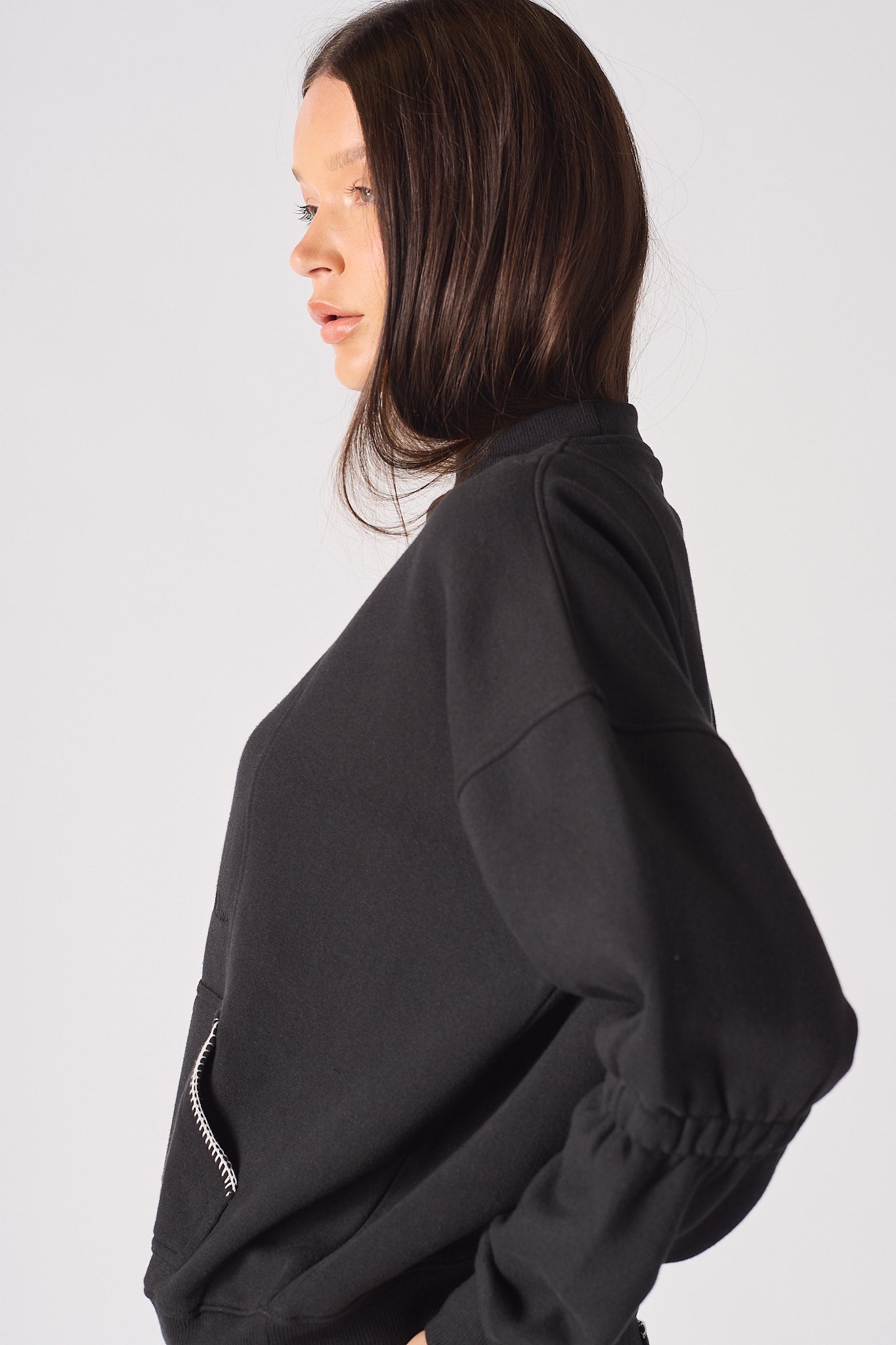 Side view showing the blanket stitch detail on the sleeves of the women's black jumper.