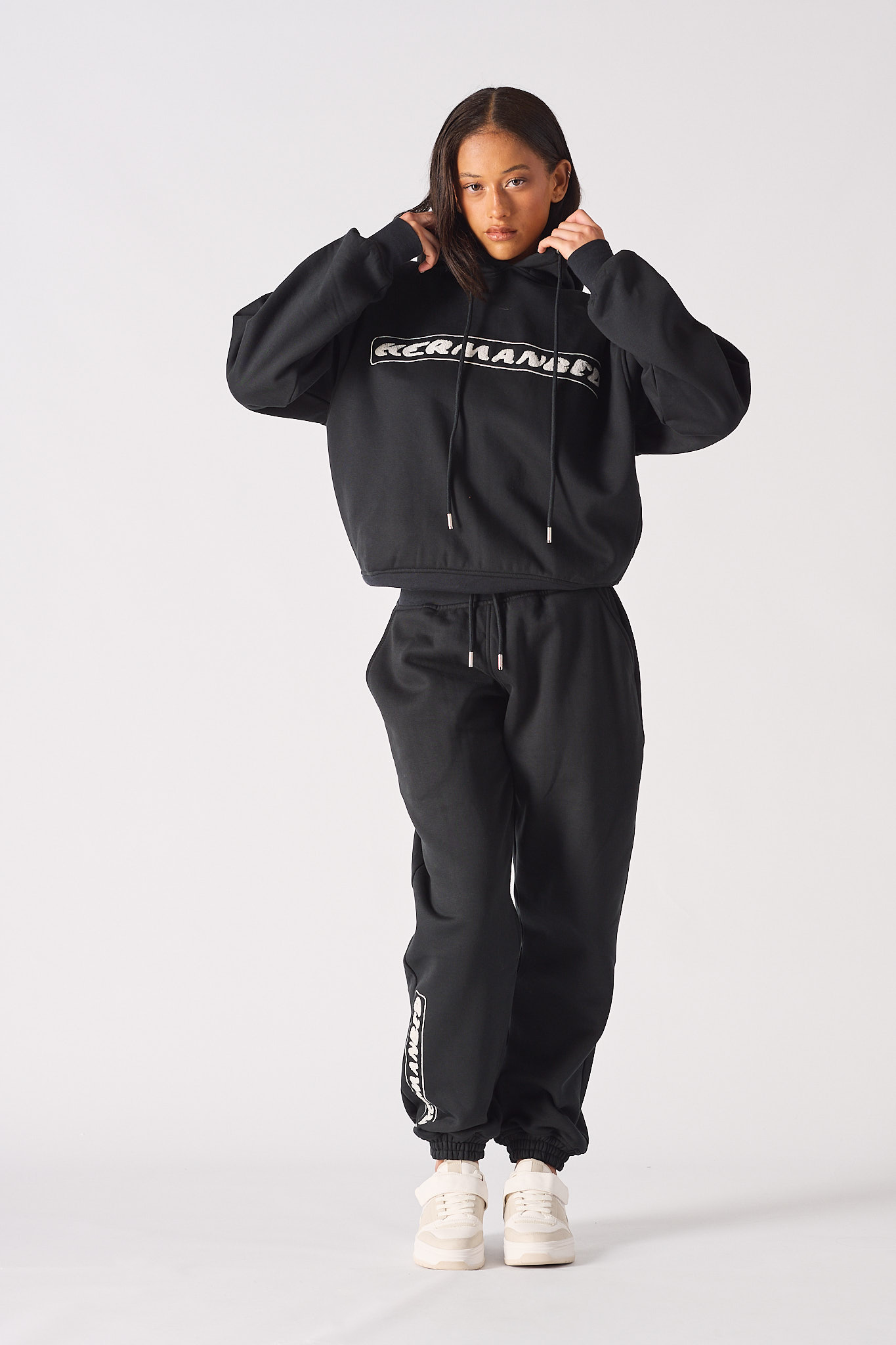 Front view of model wearing womens black oversized hoodie with matching joggers