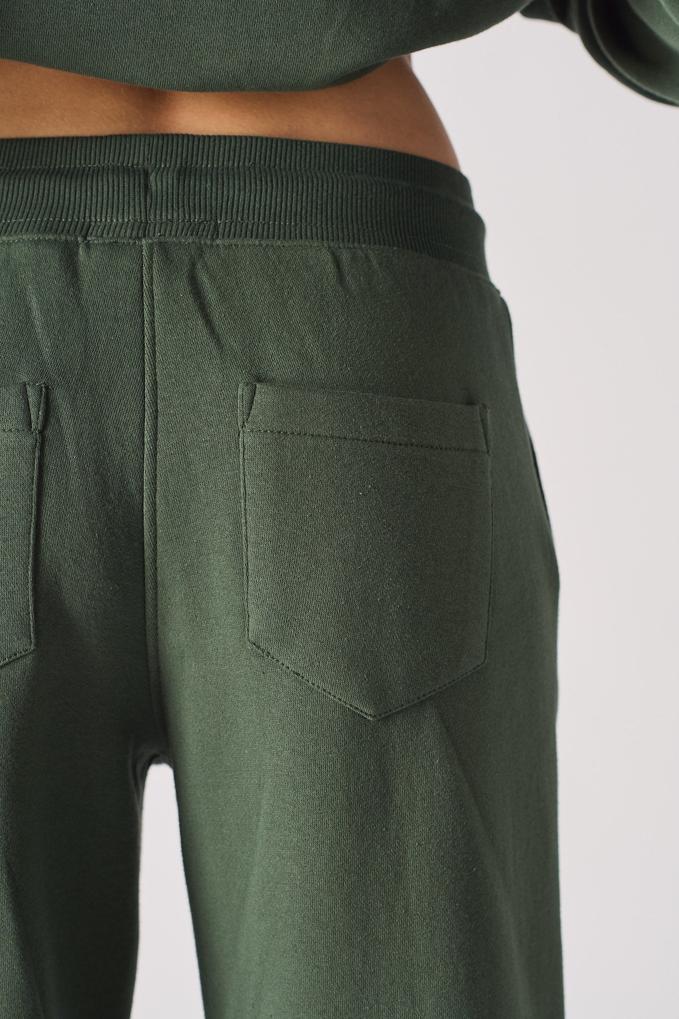 Close-up of the back pocket detail on the women's dark green joggers.