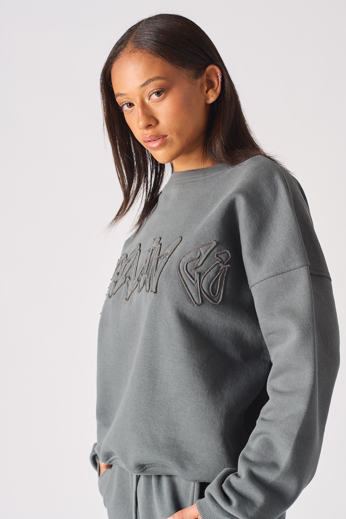 Zoomed in view of the tonal embossed branding on womens oversized grey sweatshirt