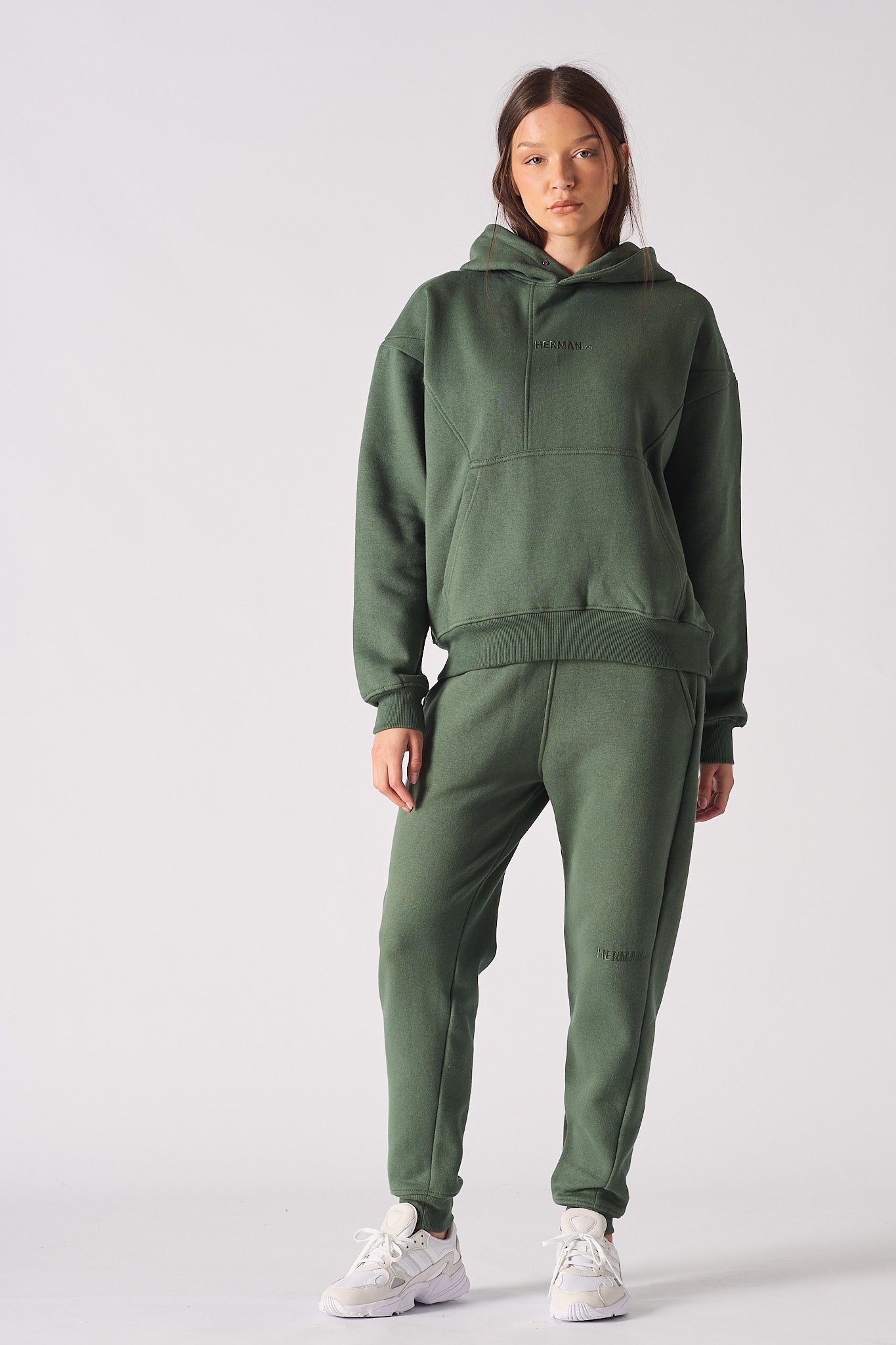 Front view of womens dark green hoodie with hands in front pocket